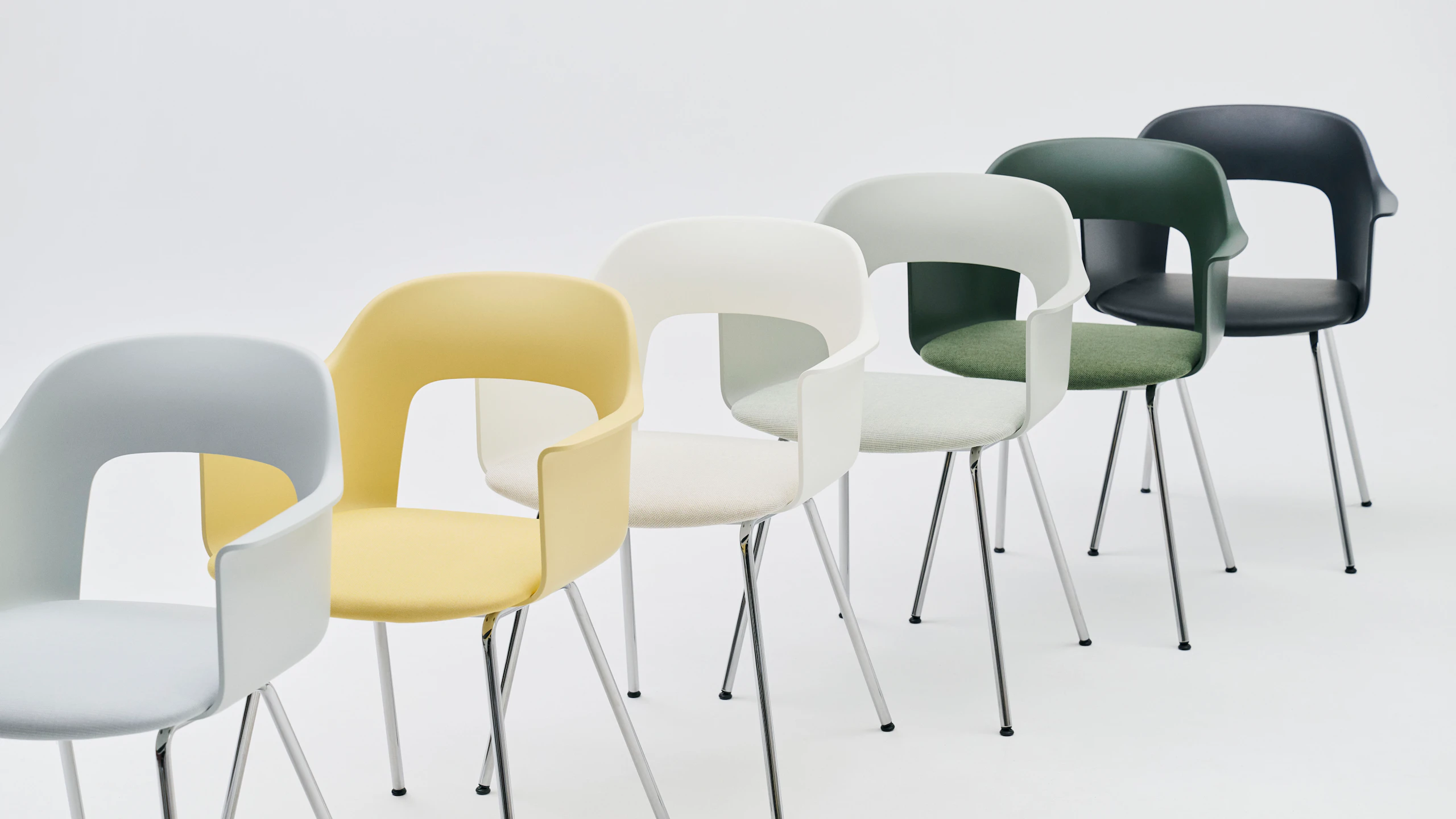 Staggered row of Layout Armchairs 213 and 234 in yellow, green, and dark blue finishes, white background.