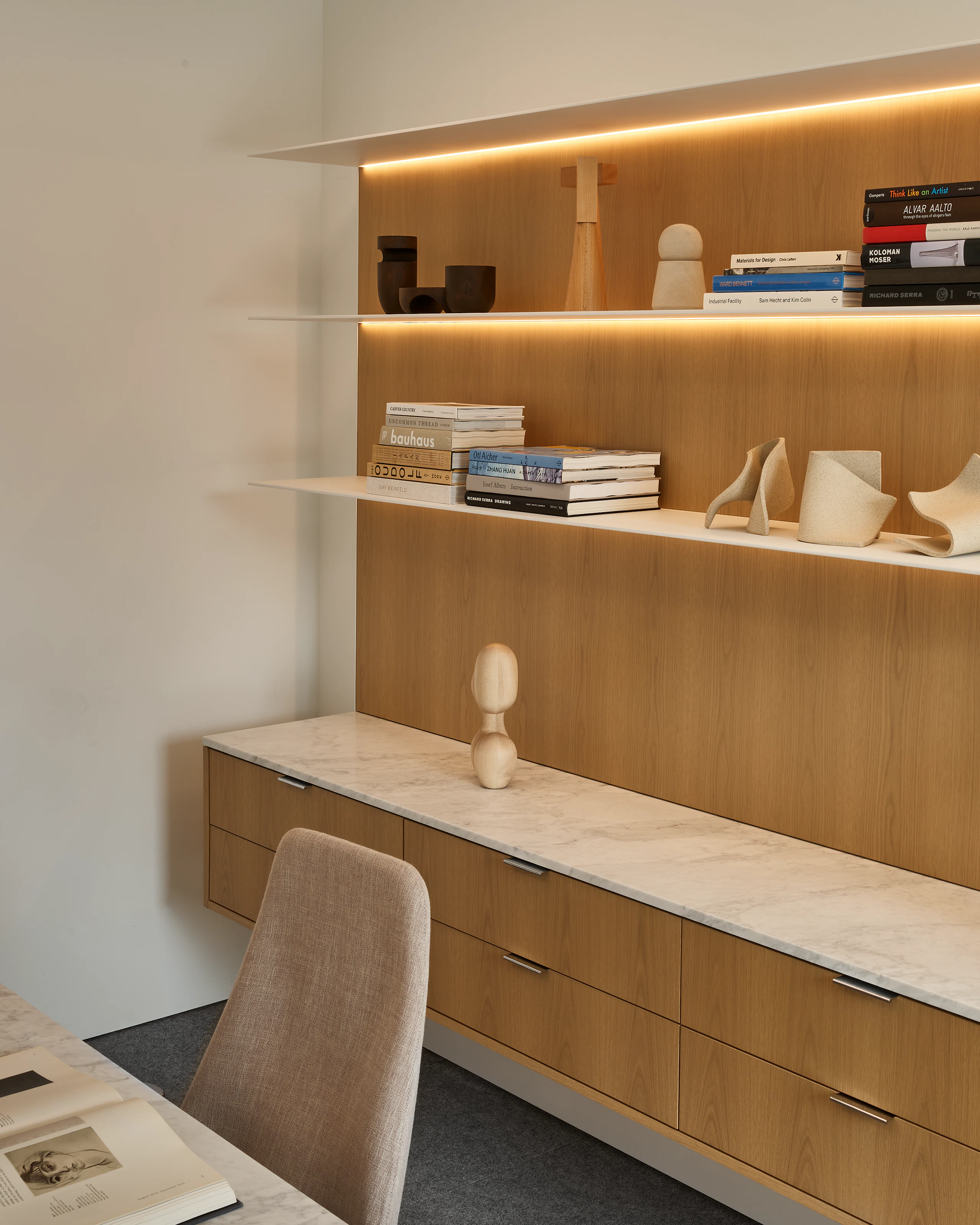 Geiger One Casegoods workwall in Nordic Oak with White Carrara Marble with a freestanding Parsons table in White Carrara Marble and chrome and Taper chair, shown at an angle in a private office setting.