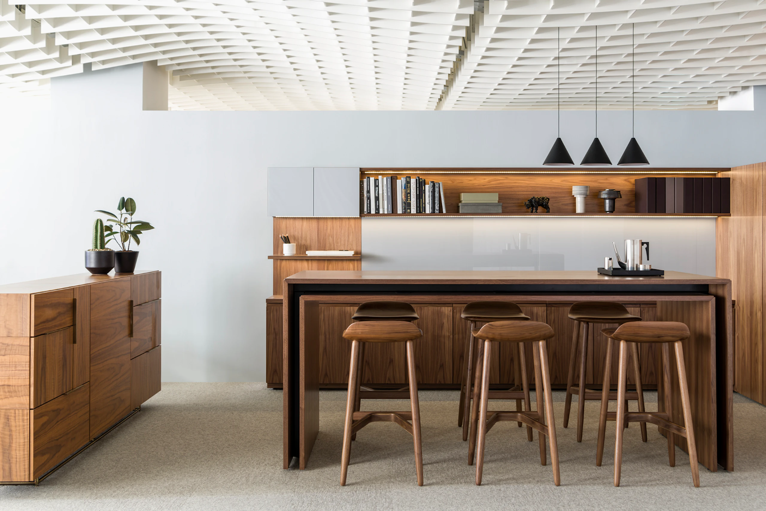 Six Crosshatch Stools with a medium finish provide seating for a standing-height Peer Table in an interaction space that includes a Domino Storage sideboard.