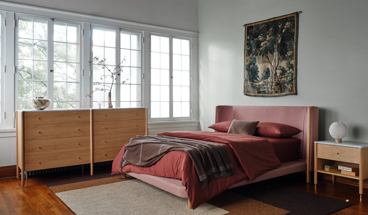 Bedroom setup with a low-profile bed, upholstered headboard, wooden wall panels, and large window view.