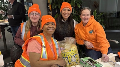 Four people wearing orange safety gear smiling for a photo.