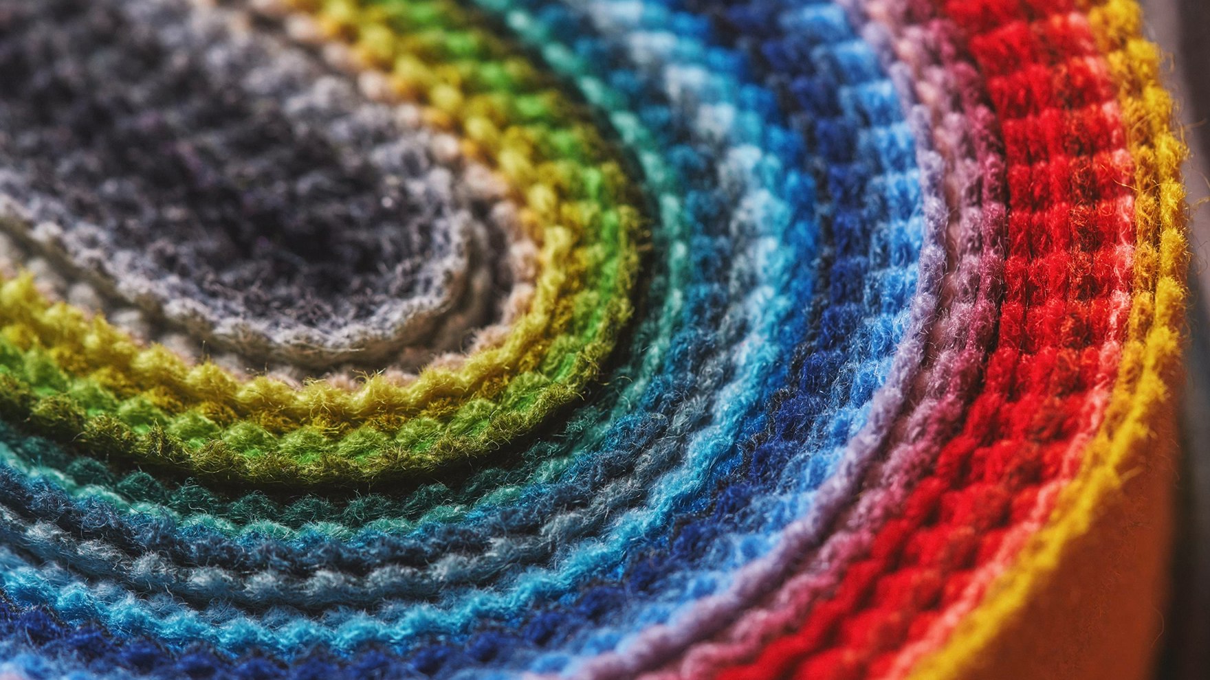 A rainbow of colorful textiles stacked on top of each other and folded into a U shape.