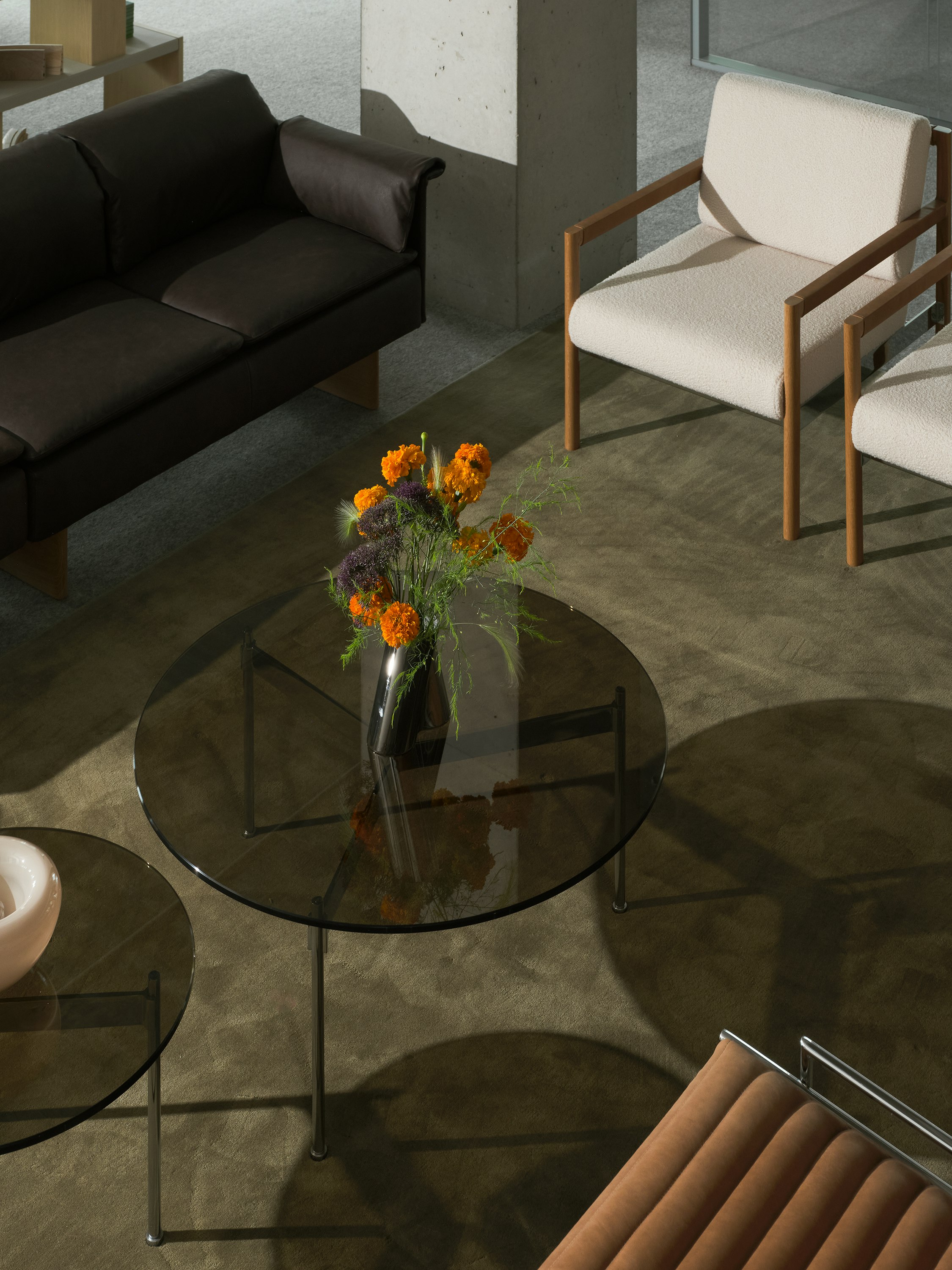 Lounge setting with two round Claw Tables, two Brabo Club Chairs, a Mantle Sectional Sofa, and a Sled Chair, viewed from above at an angle.