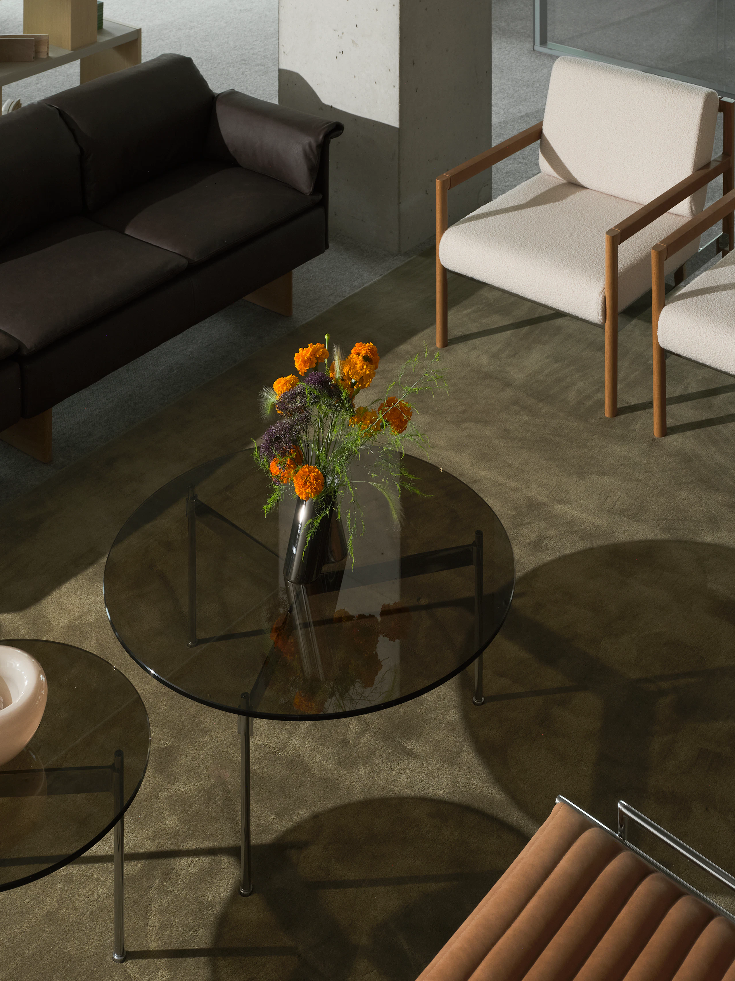 Lounge setting with two round Claw Tables, two Brabo Club Chairs, a Mantle Sectional Sofa, and a Sled Chair, viewed from above at an angle.