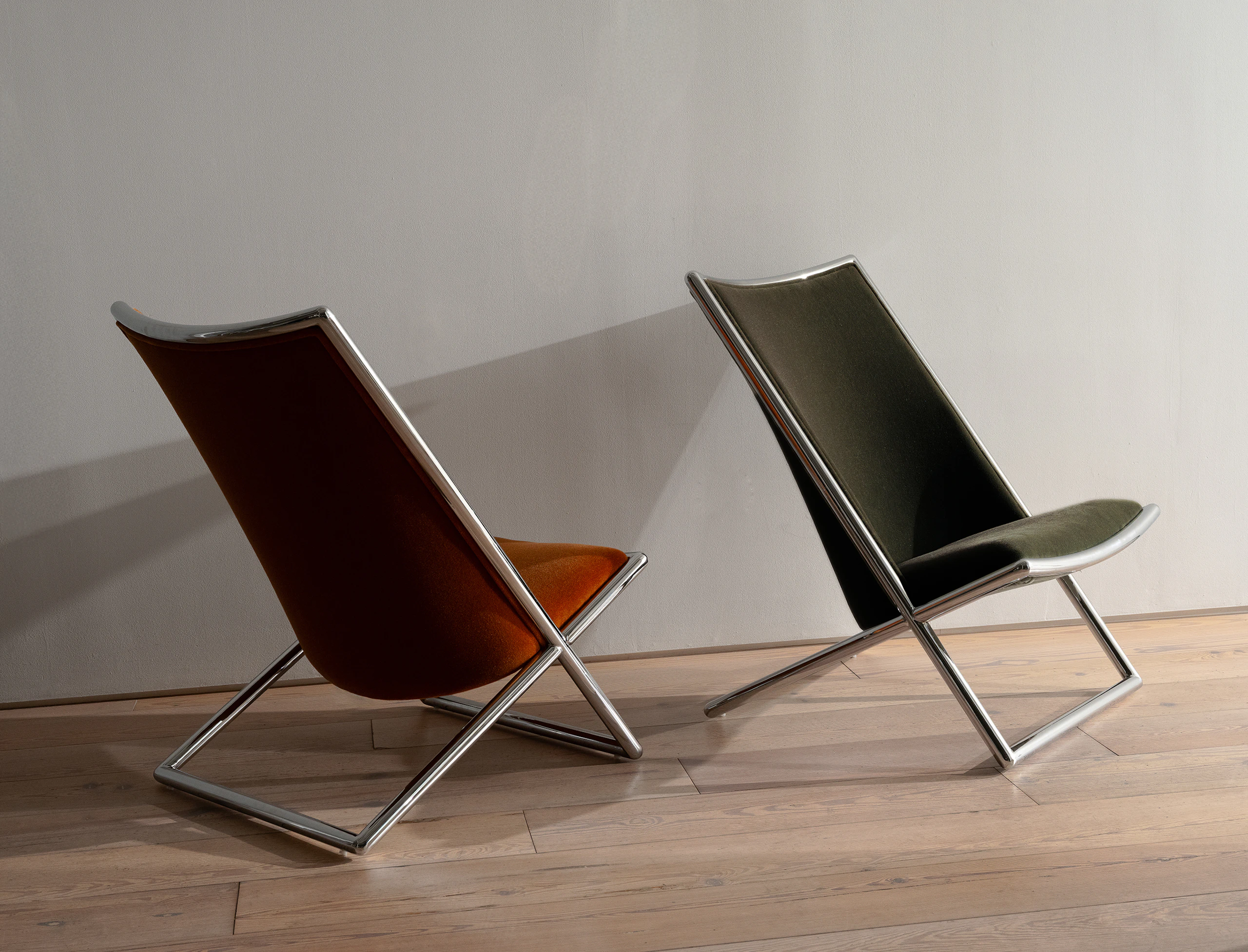 Two Scissor Chairs designed by Ward Bennett, each upholstered with Mohair Supreme, one in Cognac and one in Grassland, both with chrome frames, each positioned at different angles in a showroom setting.