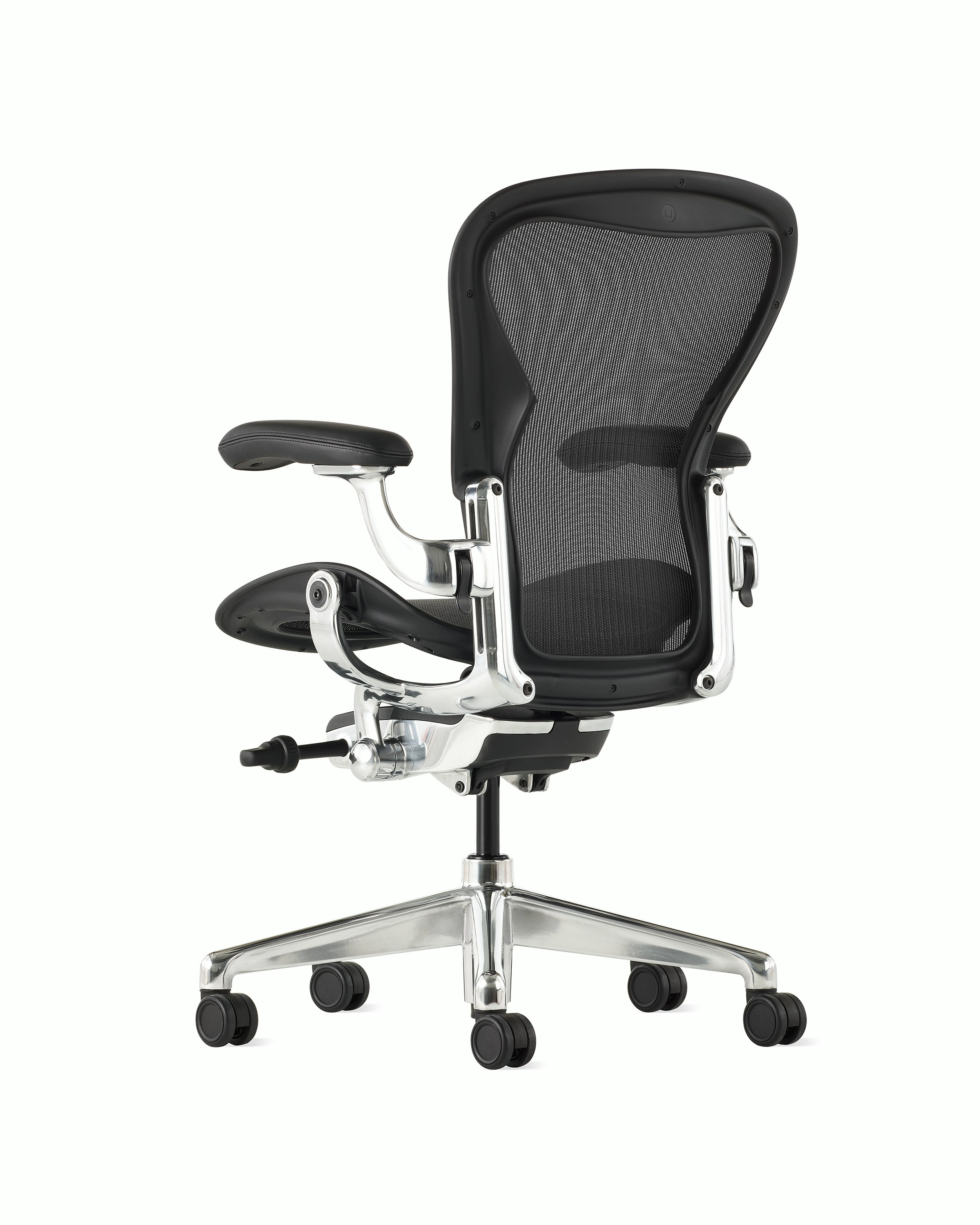 Black matte Aeron Chair on a white background with a polished aluminum 5-star base, chassis, and ergonomic back support, angled view of chair back.