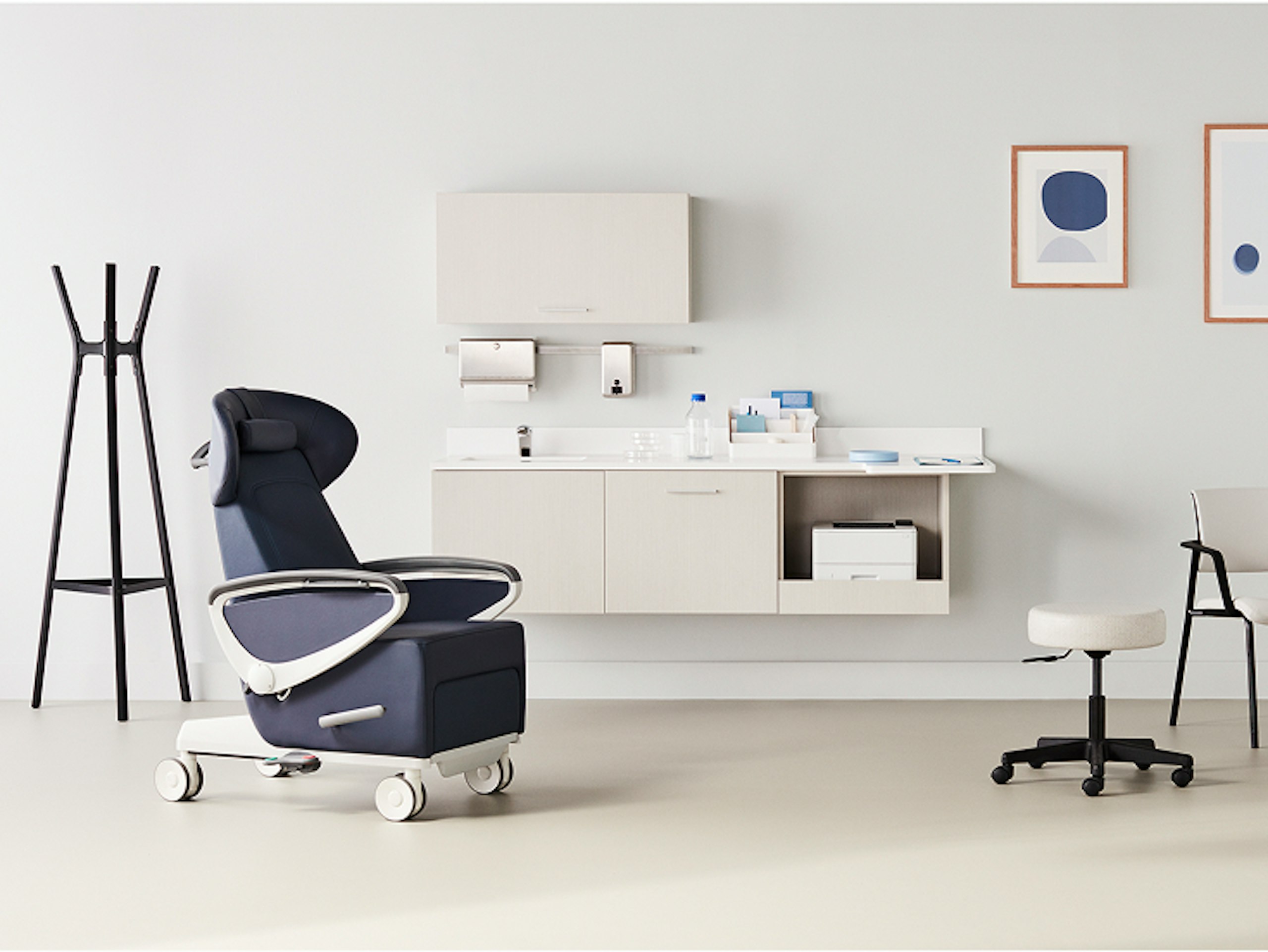 Exam room with a dark blue Ava recliner and an Intent Solution mobile, height-adjustable table and wall unit to the side with a physician stool and Verus side chair