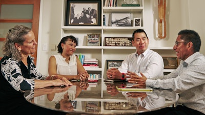 A group of people sitting around a Saarinen Dining Table, Oval by Knoll, engaging in conversation.