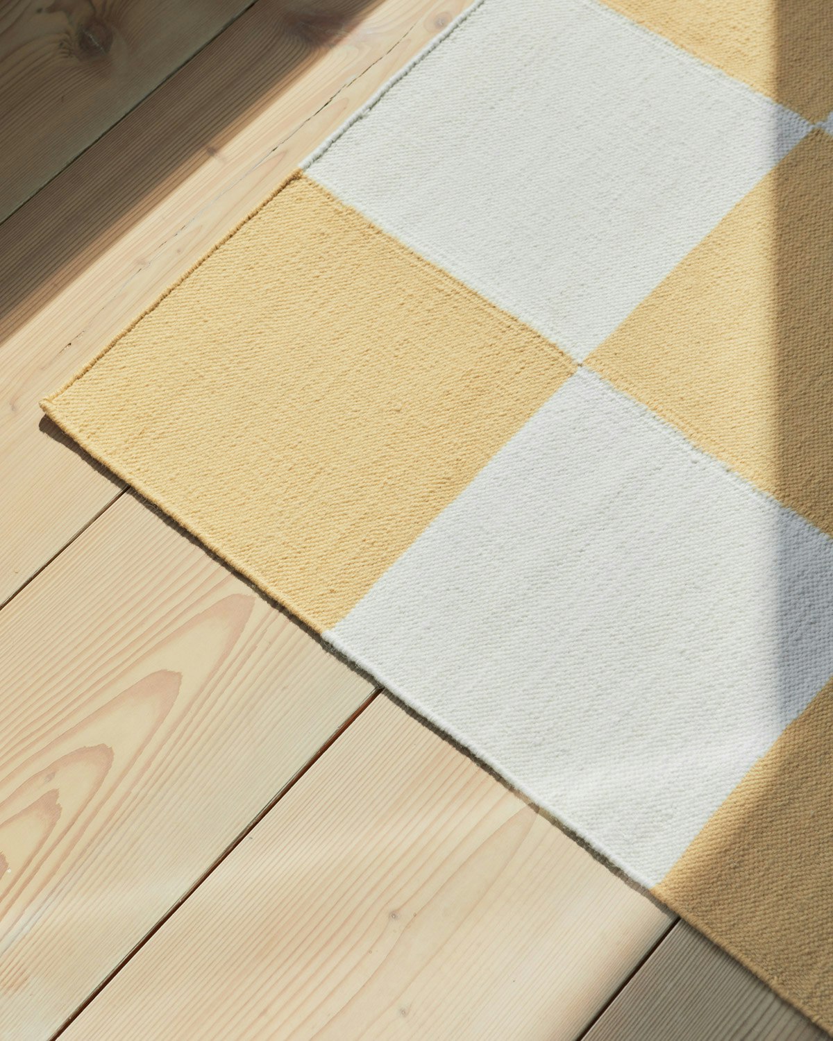 An environmental shot of the Square Flatweave Rug in Yellow.