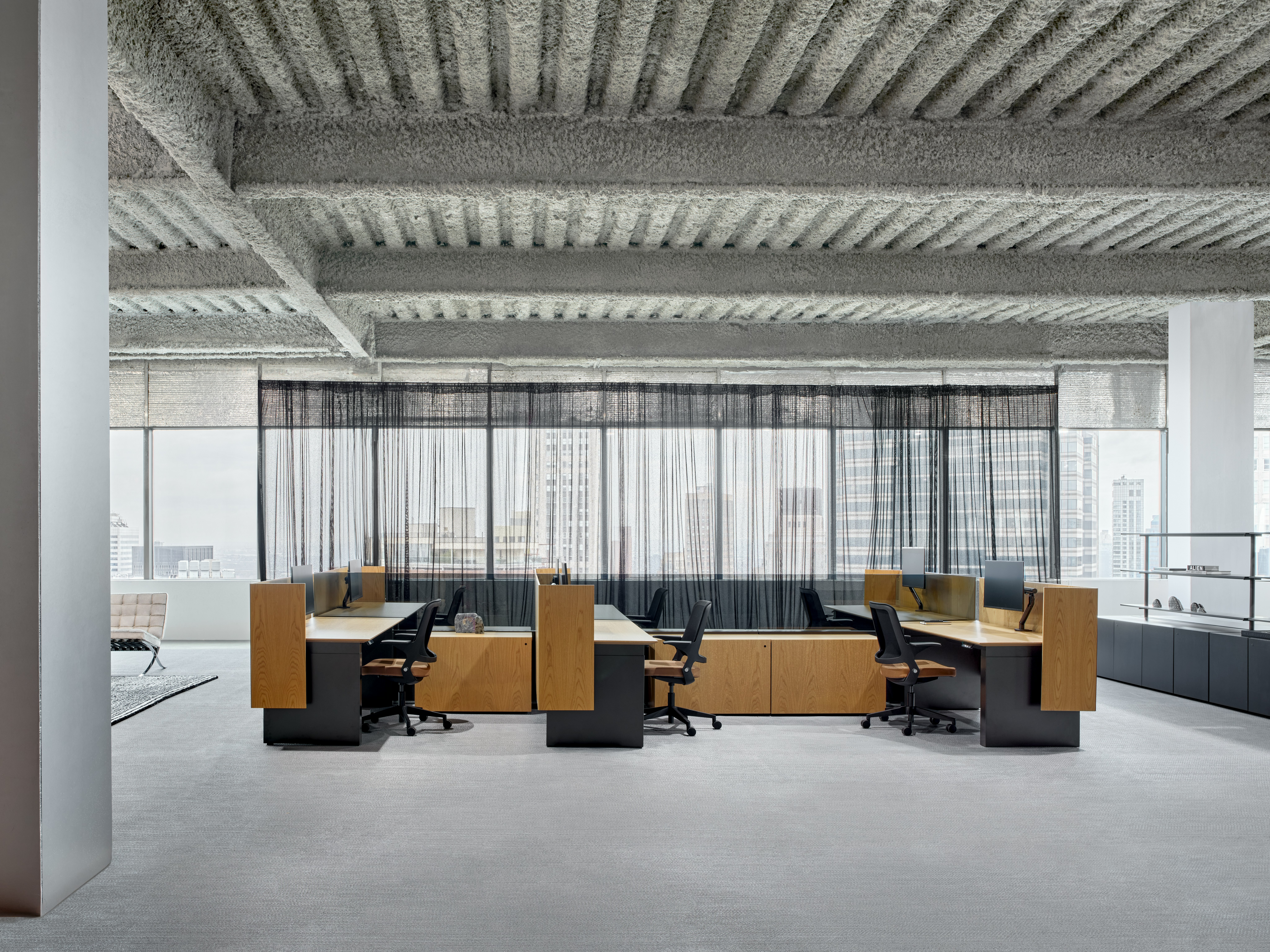 A six pack of workstations is in an open office setting, along with shared storage credenzas and open shelving to the side of the work stations.