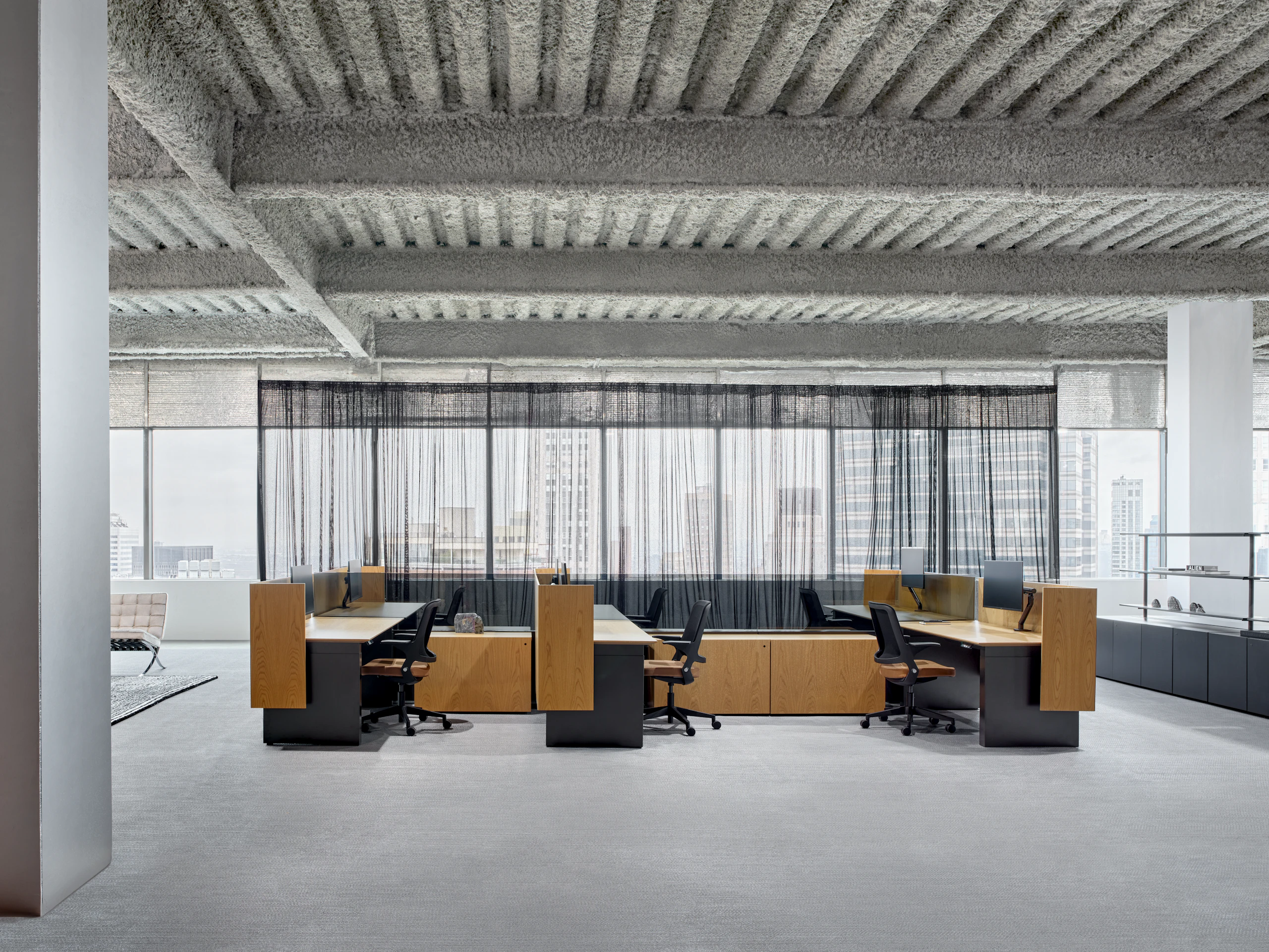 A six pack of workstations is in an open office setting, along with shared storage credenzas and open shelving to the side of the work stations.