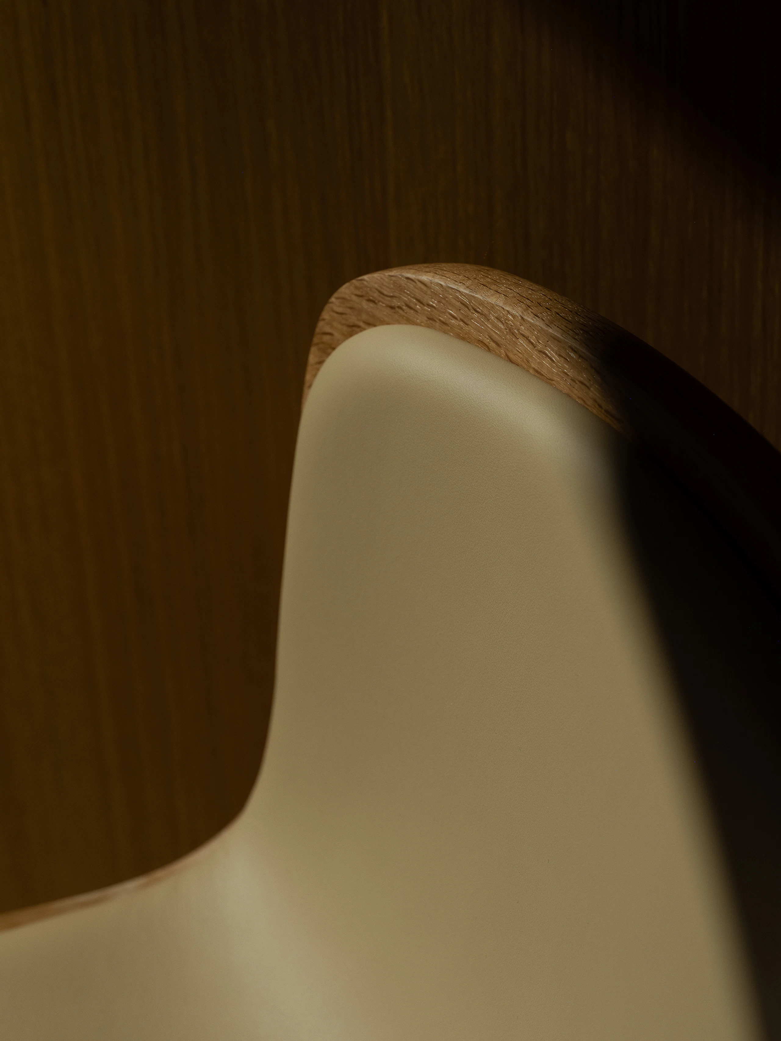 Detail view of a Lijn Stool seat and backrest in Natural Oak fully upholstered with Bristol leather in Champagne, viewed from above.