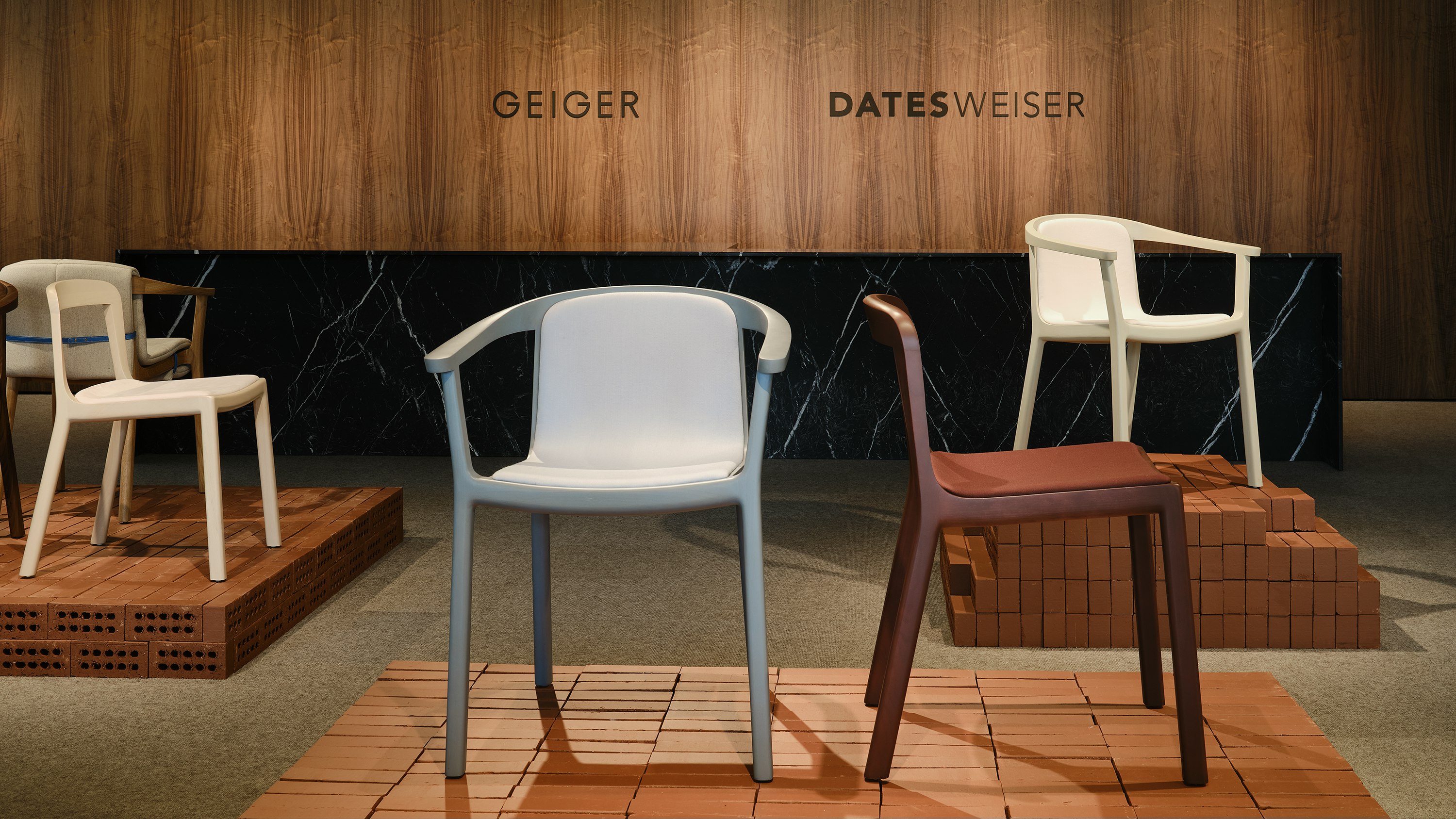 Lijn Armchairs and Side Chairs designed by Carole Baijings in assorted finishes on exhibition platforms, shown at various angles, in the Geiger showroom.