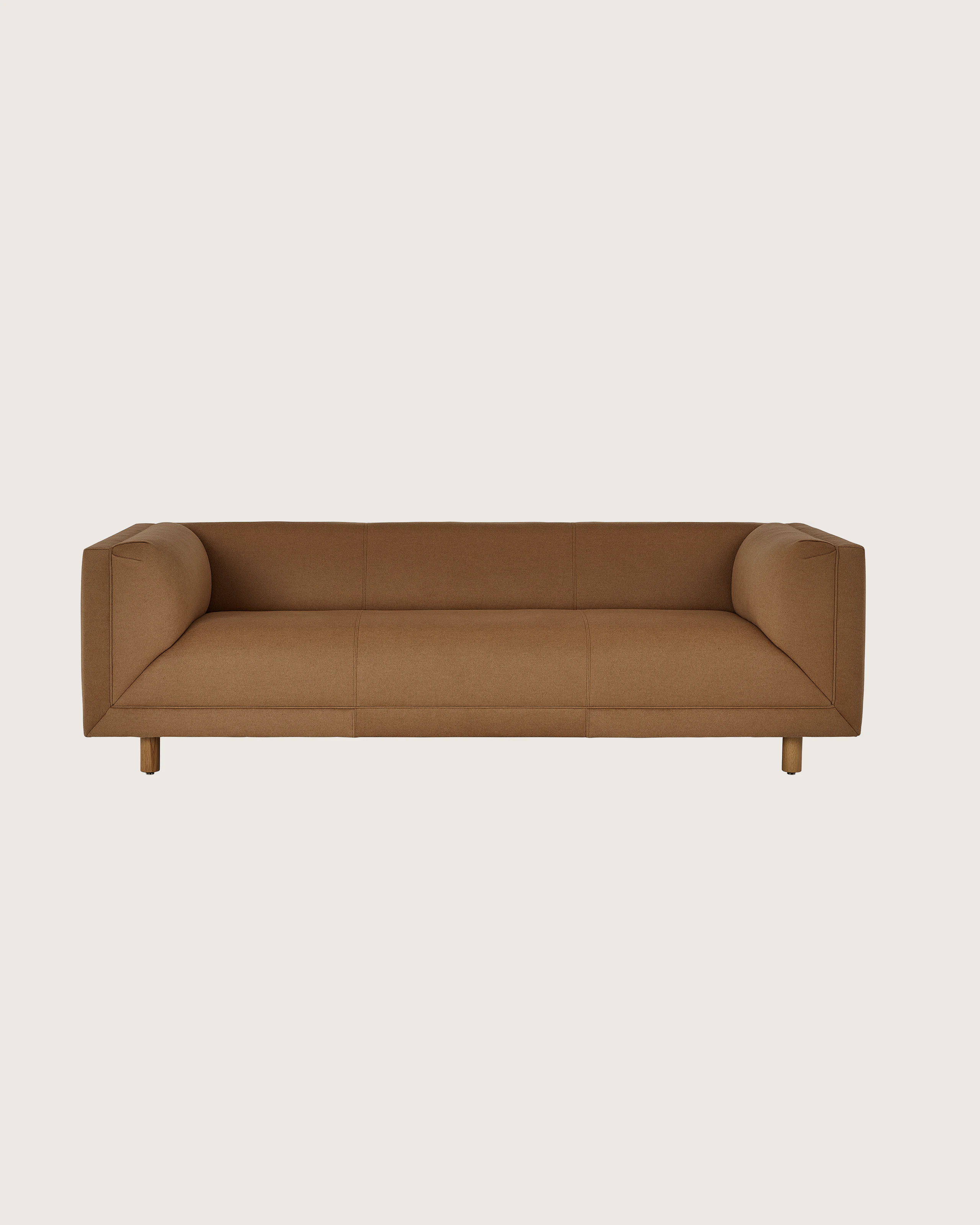 Rolled Arm Sofa designed by Ward Bennett upholstered in Brushed Camel in Natural with a Natural Oak base, shown front-facing on a white sweep.