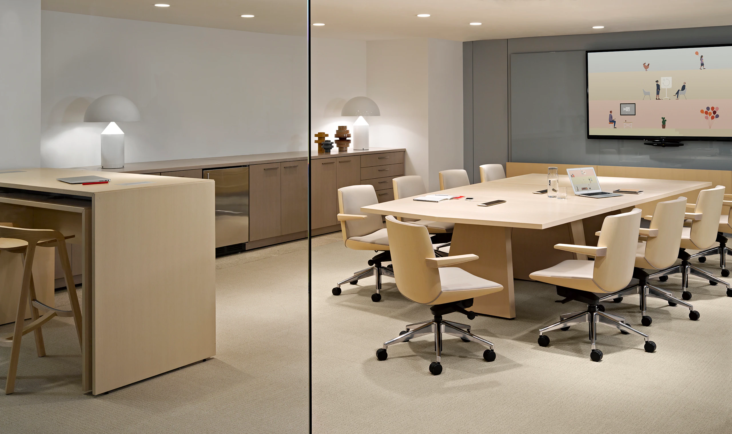 A large wall-hung monitor overlooks a Geiger Elsi video conference table surrounded by several ivory-colored Clamshell office chairs.