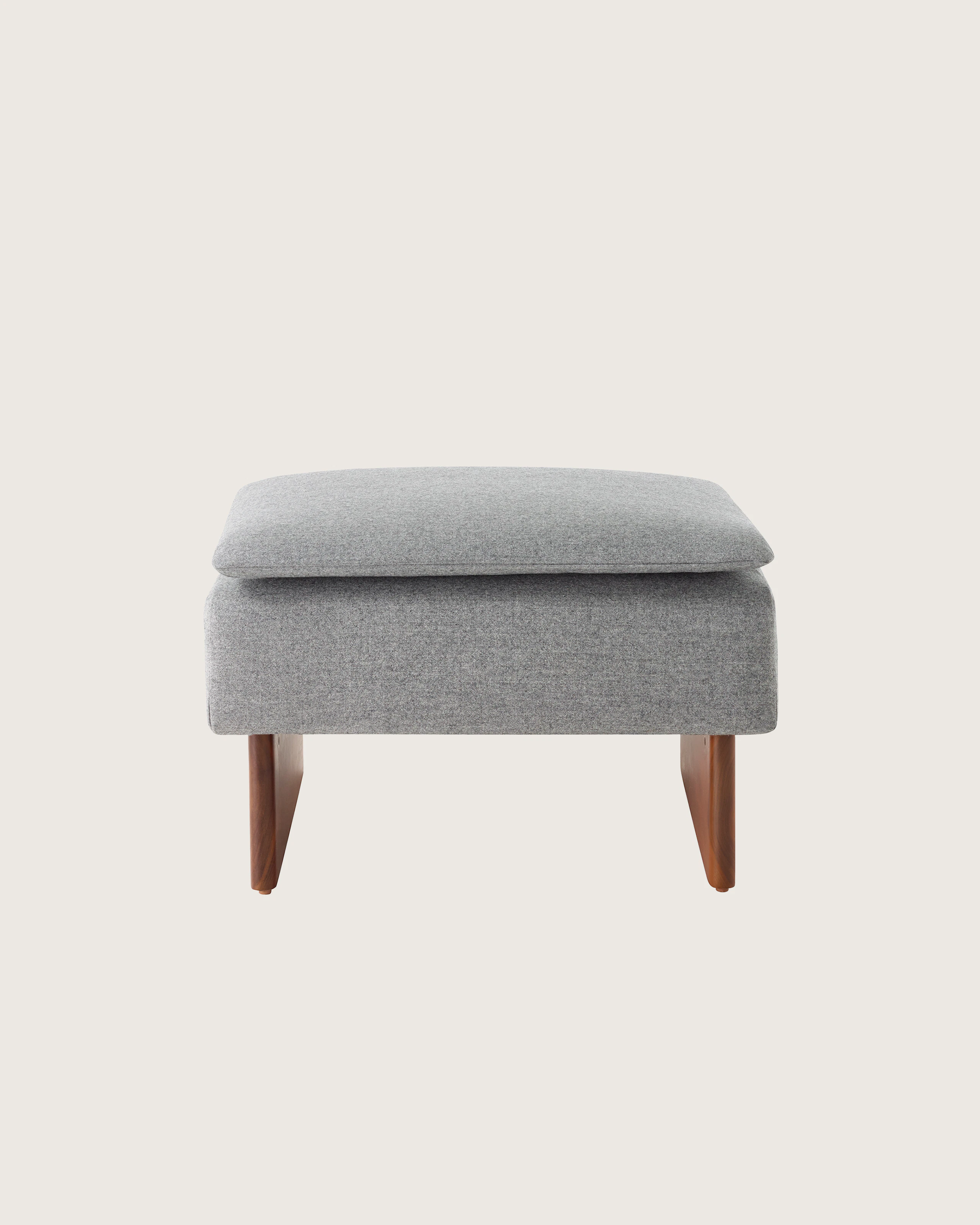 Mantle Ottoman in Panno di Dolce Flannel with a Walnut Base, viewed from the front.