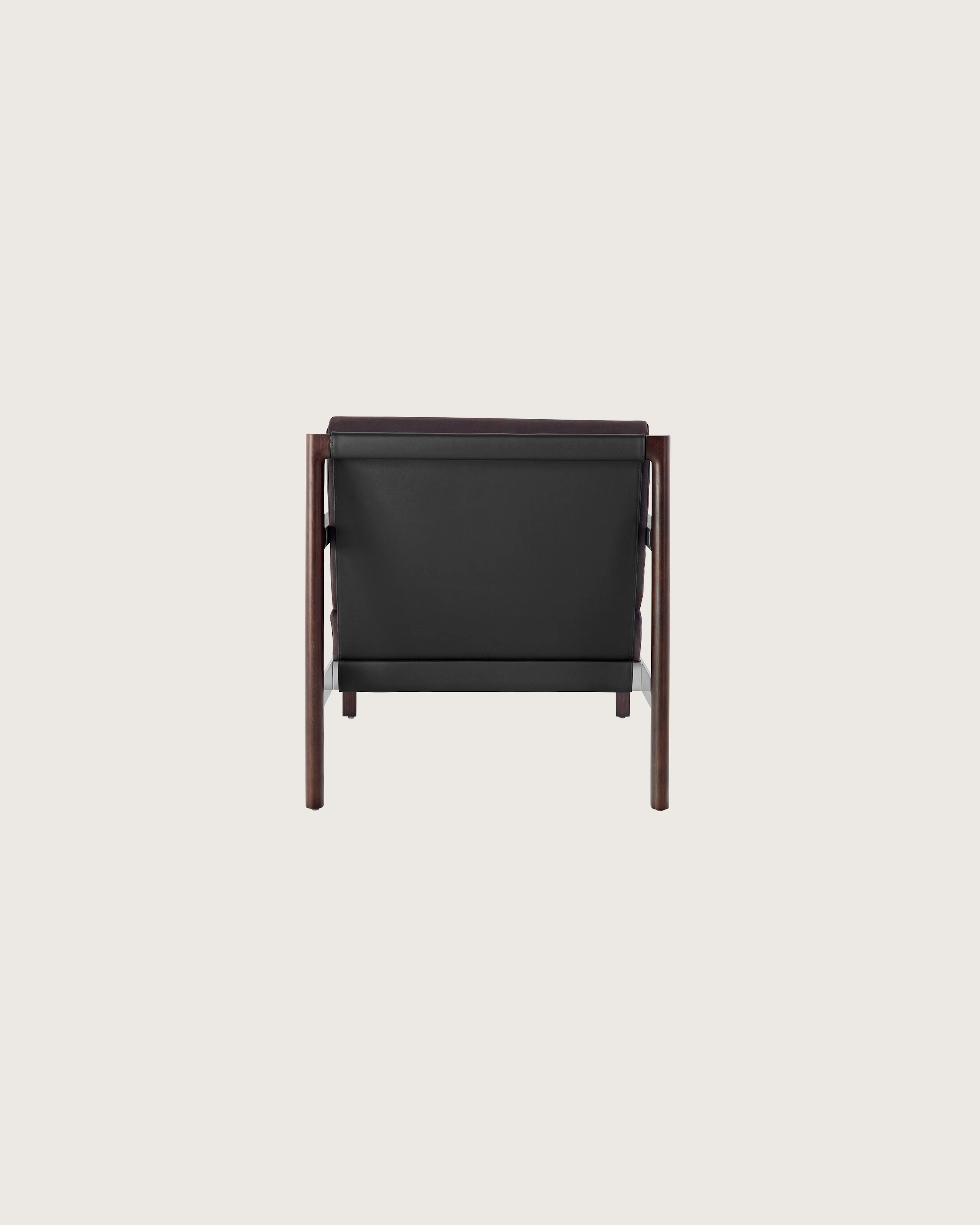 A Brabo club chair with a black leather sling, metal accents, and an exposed wood frame, viewed from behind.