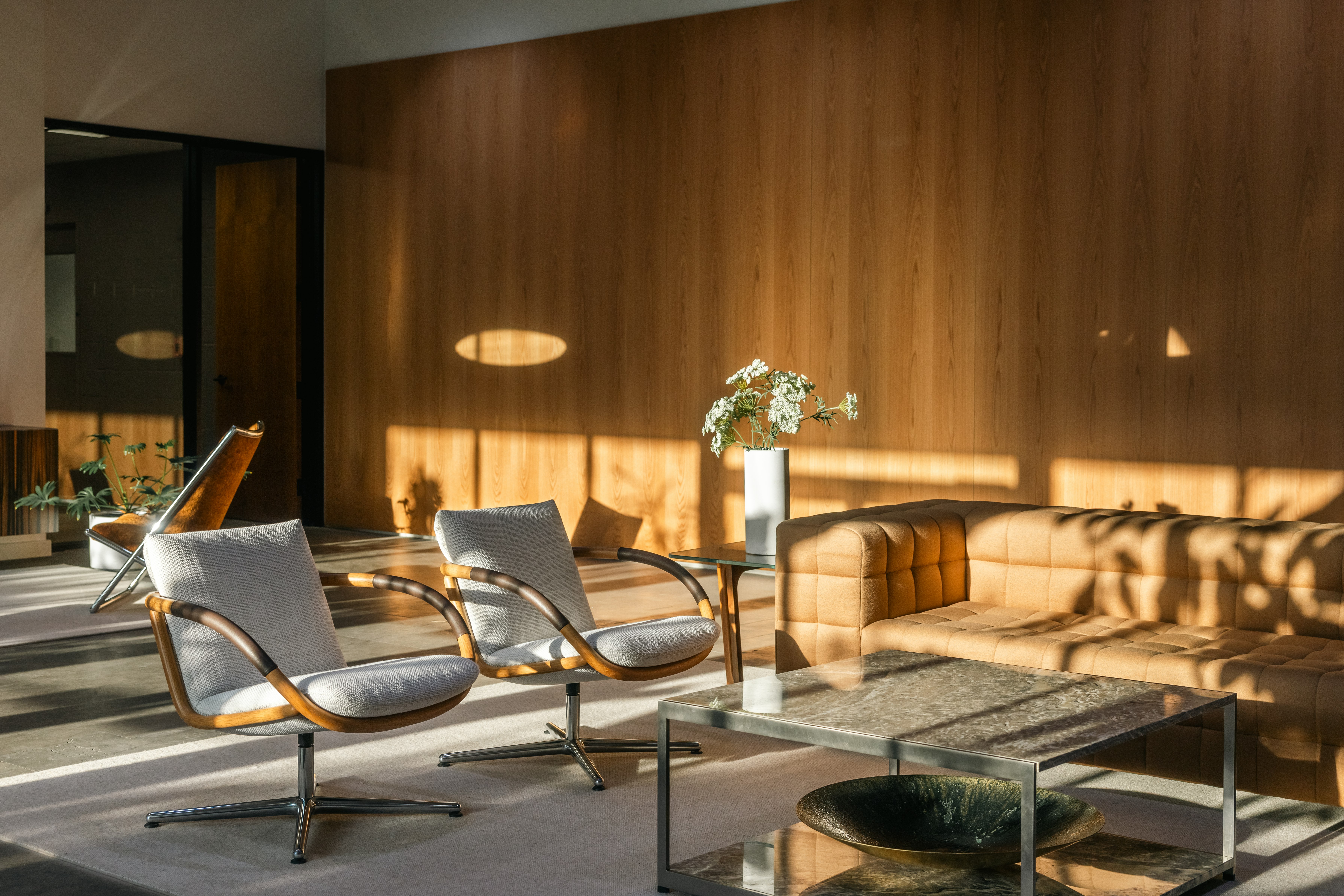 Lounge setting featuring Two Full Loop Lounge Chairs, an H Frame Coffee Table, and a Rapport Sofa viewed from an angle in a showroom.