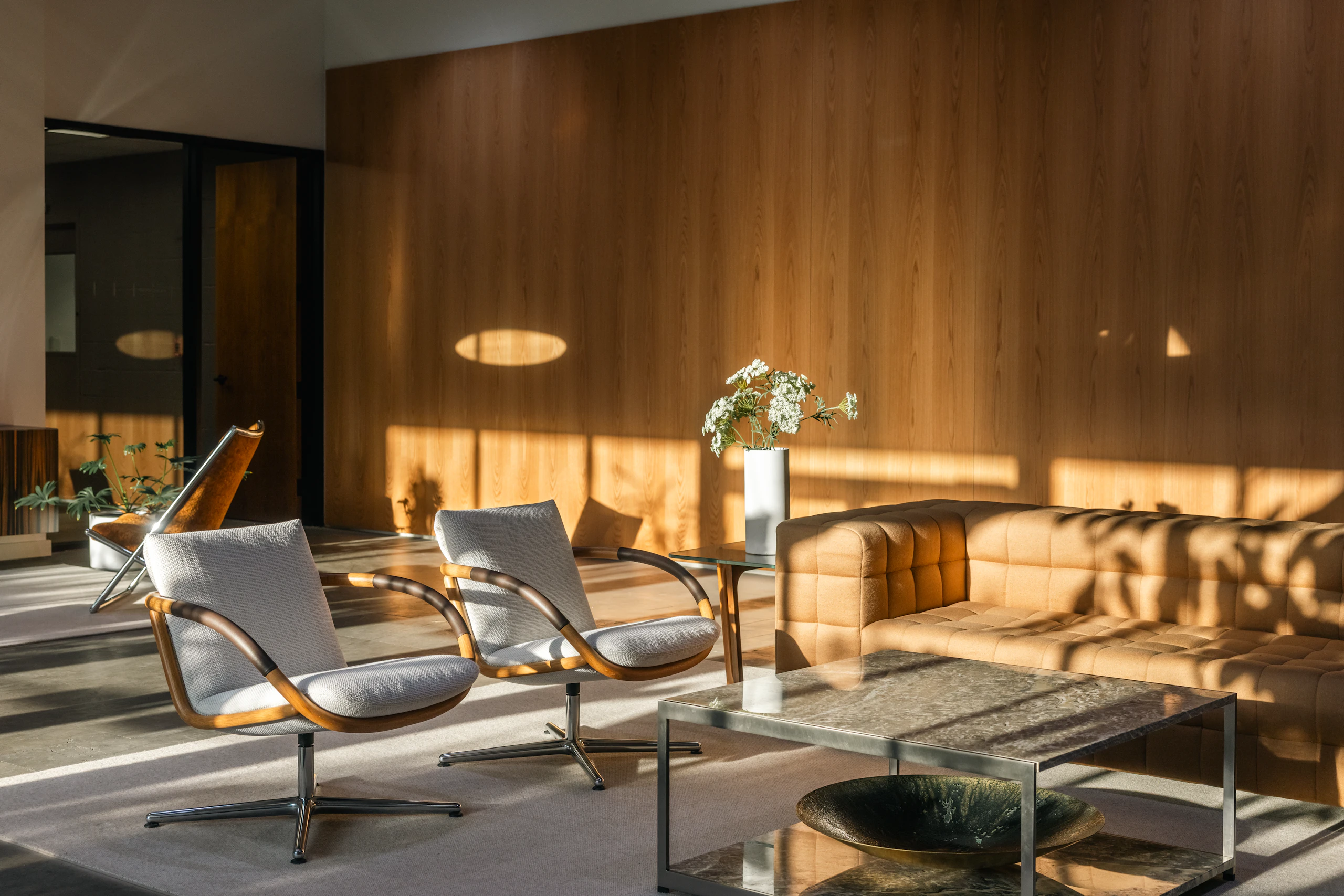 Lounge setting featuring Two Full Loop Lounge Chairs, an H Frame Coffee Table, and a Rapport Sofa viewed from an angle in a showroom.