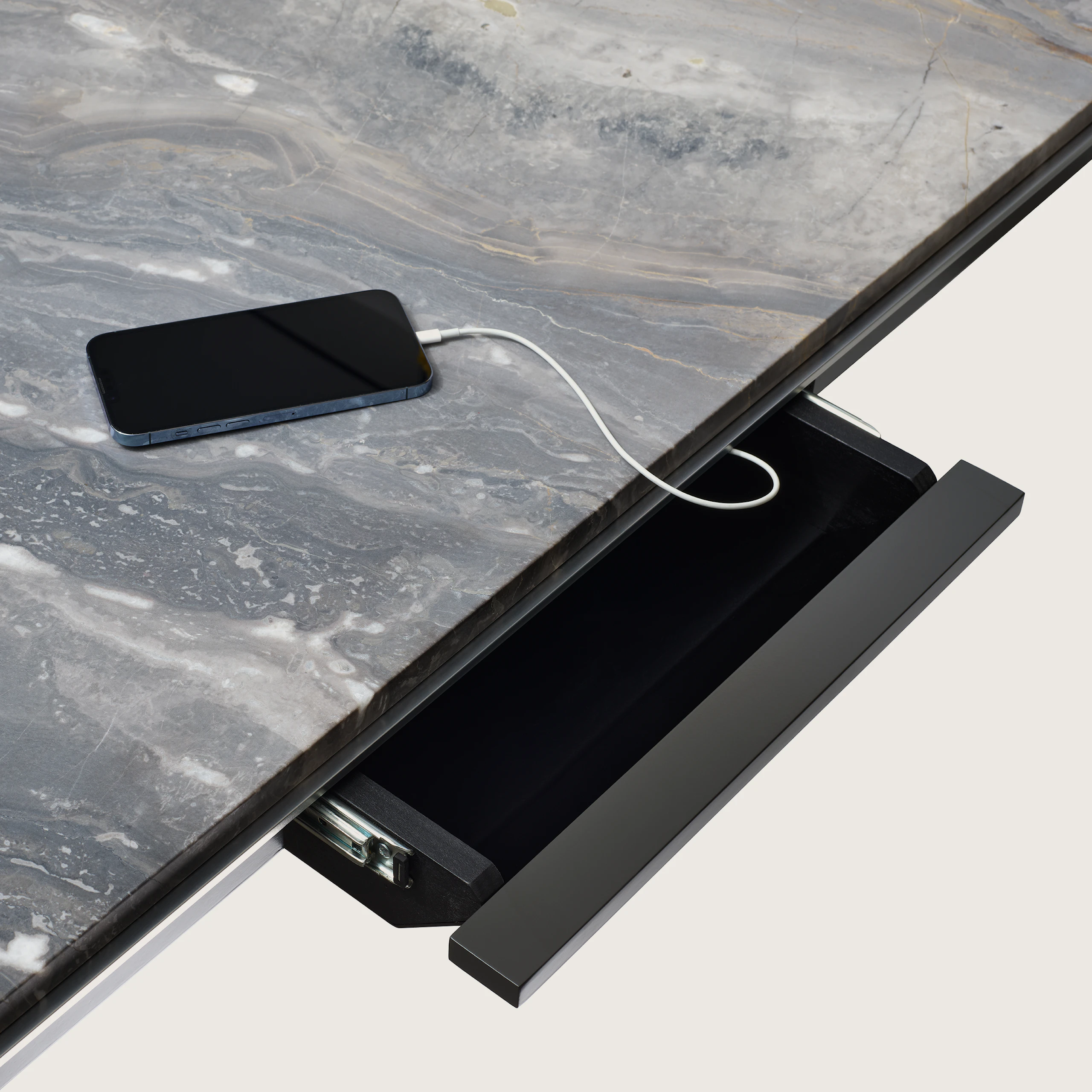 Detail view of open power drawer charging an iPhone on a Highline Conference Table with a Marble top and polished chrome edge.