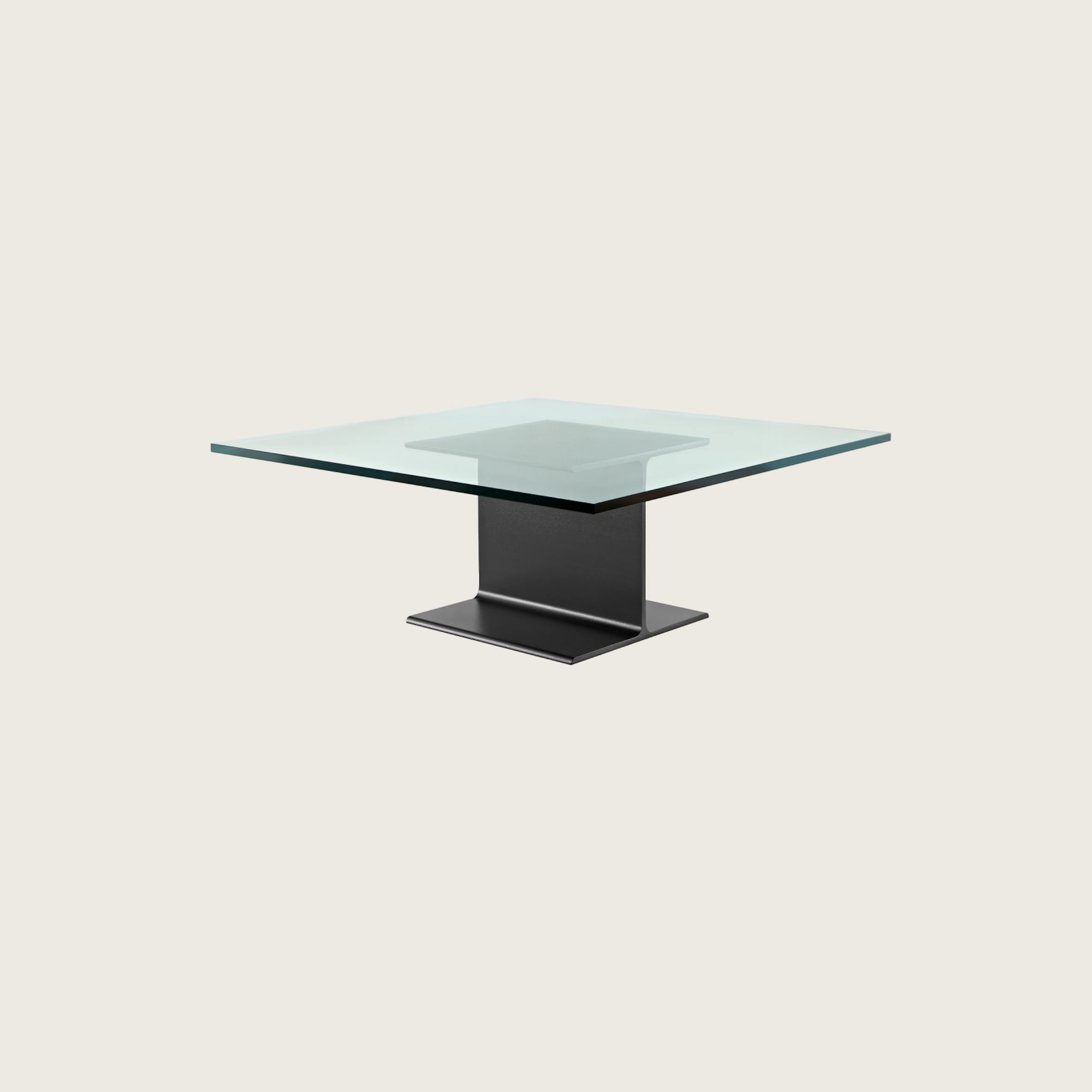 Partial angled view of a square I Beam coffee table with a glass top and black cast-aluminum pedestal.