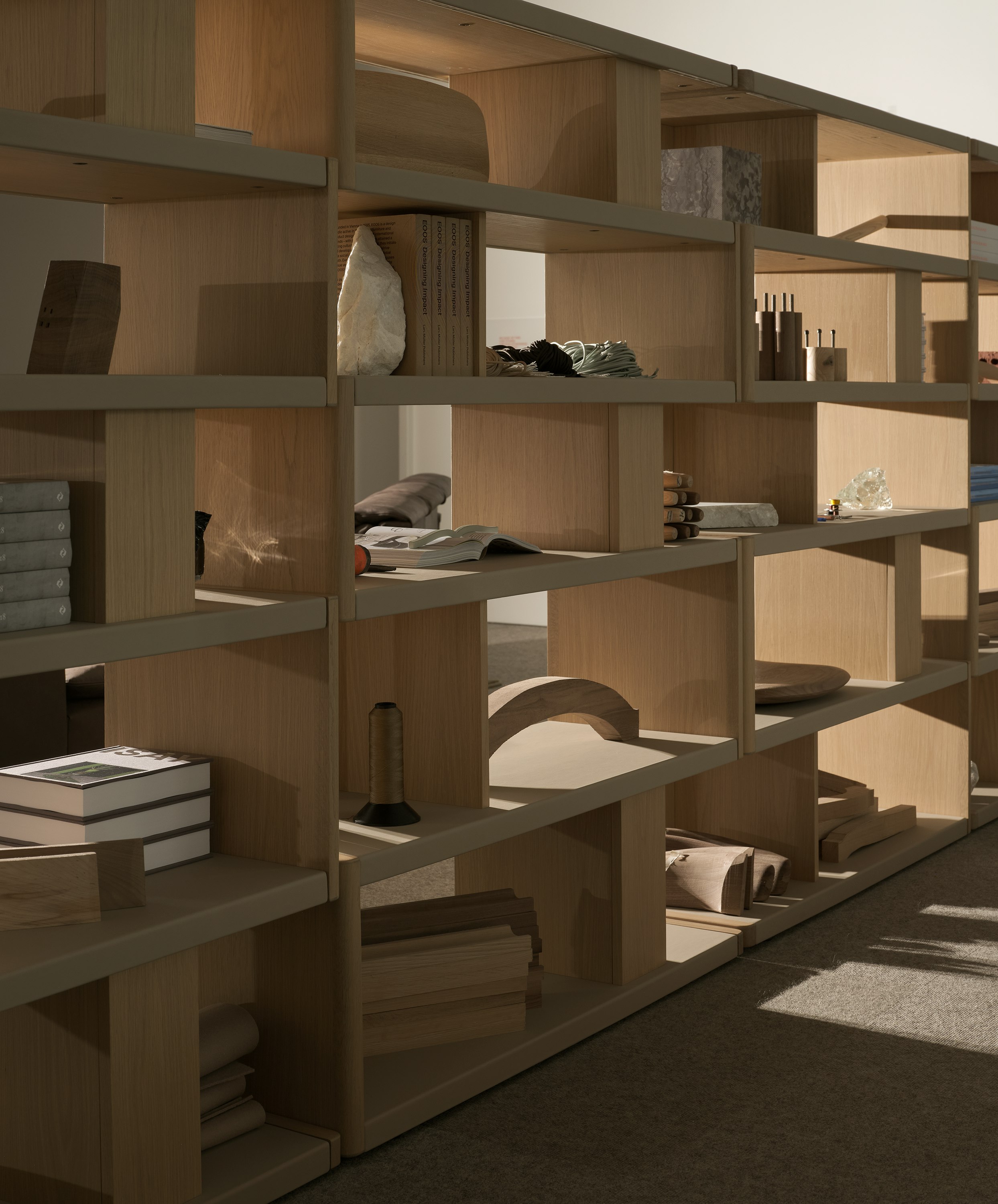 Various New Canaan Tall Bookshelves in Light Oak wrapped with Bristol Leather in Champagne arranged side by side and styled with various objects, viewed at an angle.