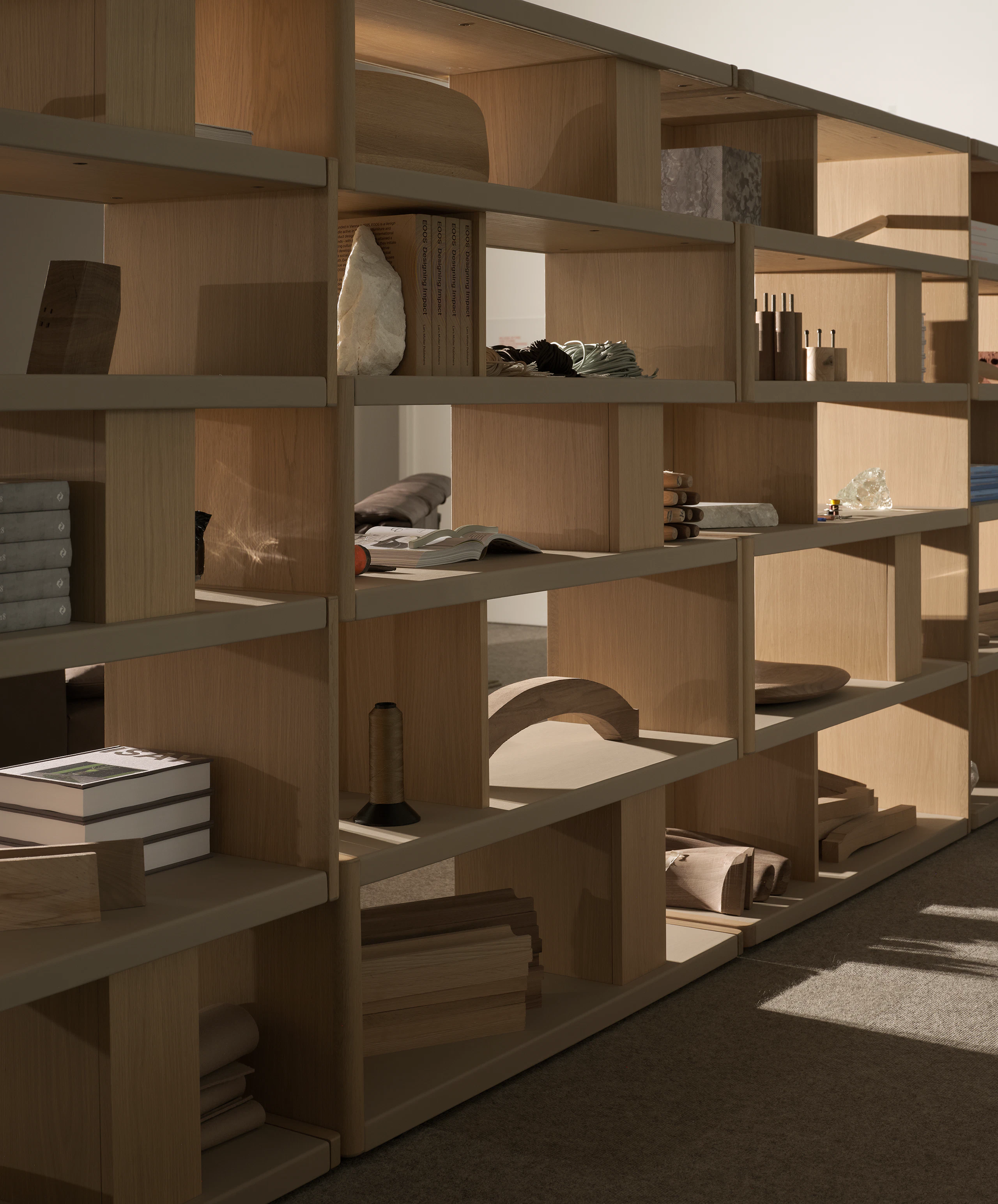 Various New Canaan Tall Bookshelves in Light Oak wrapped with Bristol Leather in Champagne arranged side by side and styled with various objects, viewed at an angle.
