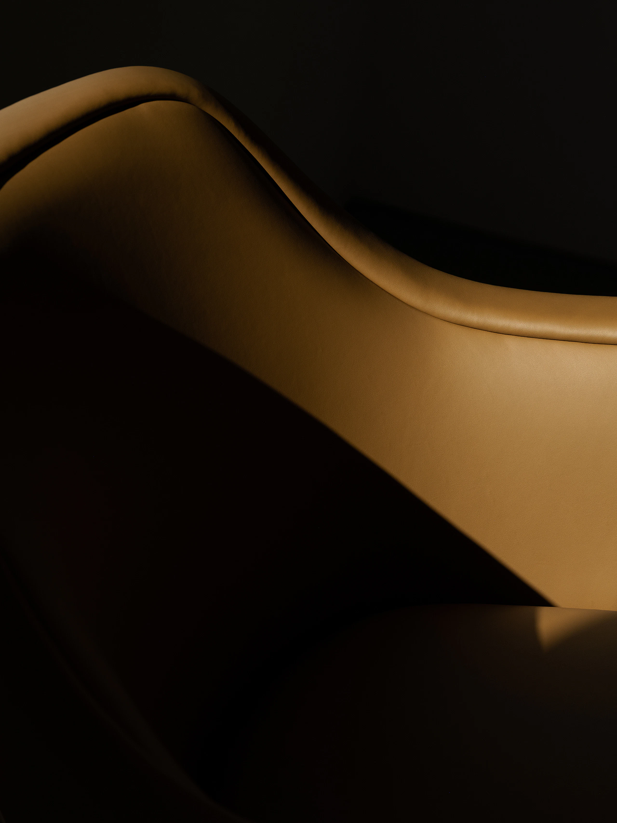 Detail view of a Bumper Lounge Chair with low arms upholstered with Pace Leather in Toffee.
