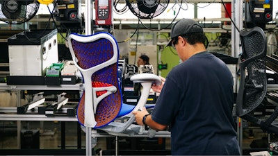 An employee assembling a Mirra 2 Chair by Herman Miller on the production line.