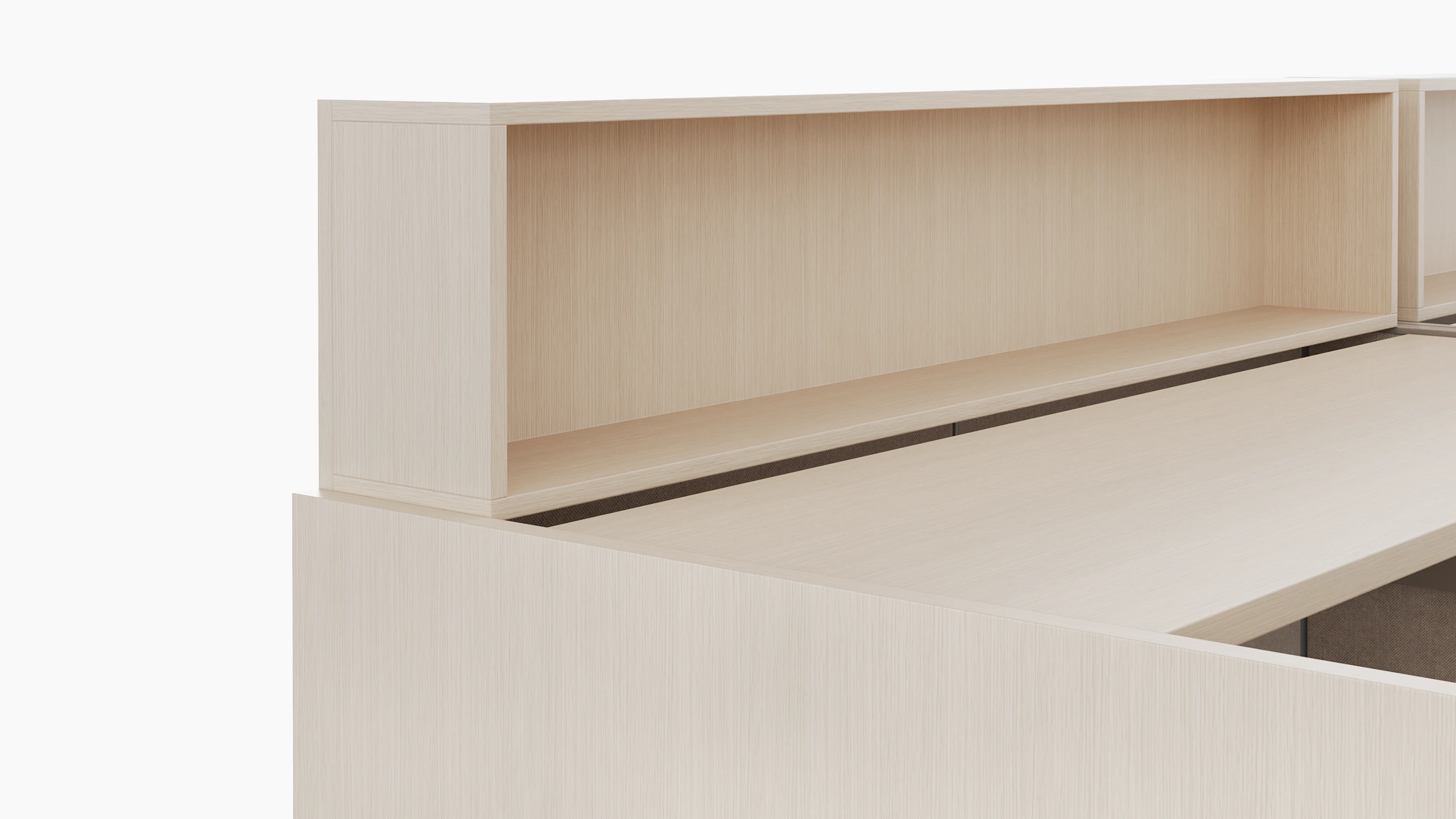 A height adjustable work surface is viewed from an angle. On top of the work surface is a personal storage cubby in a light color veneer.
