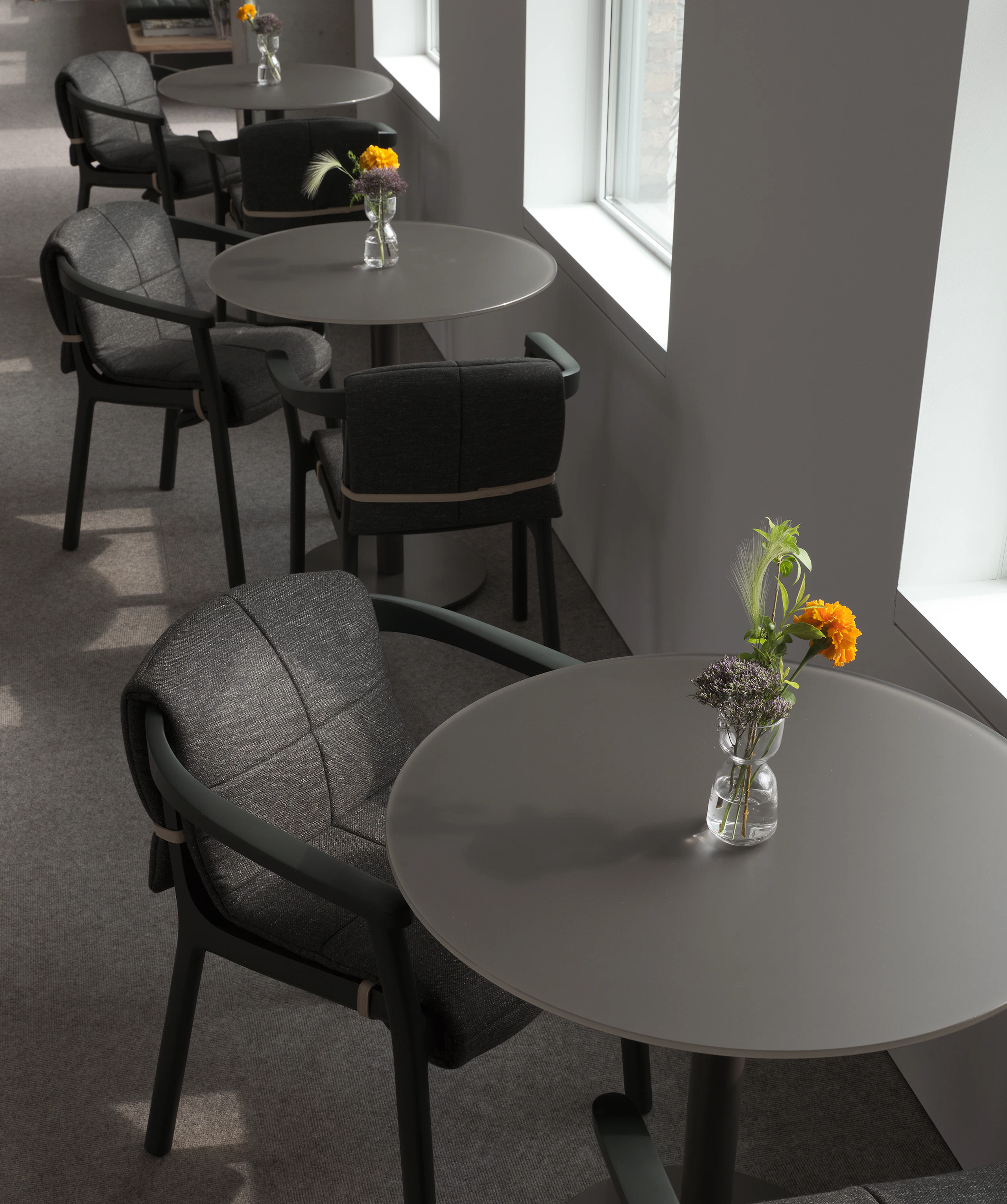 Lijn Armchairs in Ivy with quilted wraps in Bellano Black Green with NL tables in a cafe setting, viewed from above at an angle.