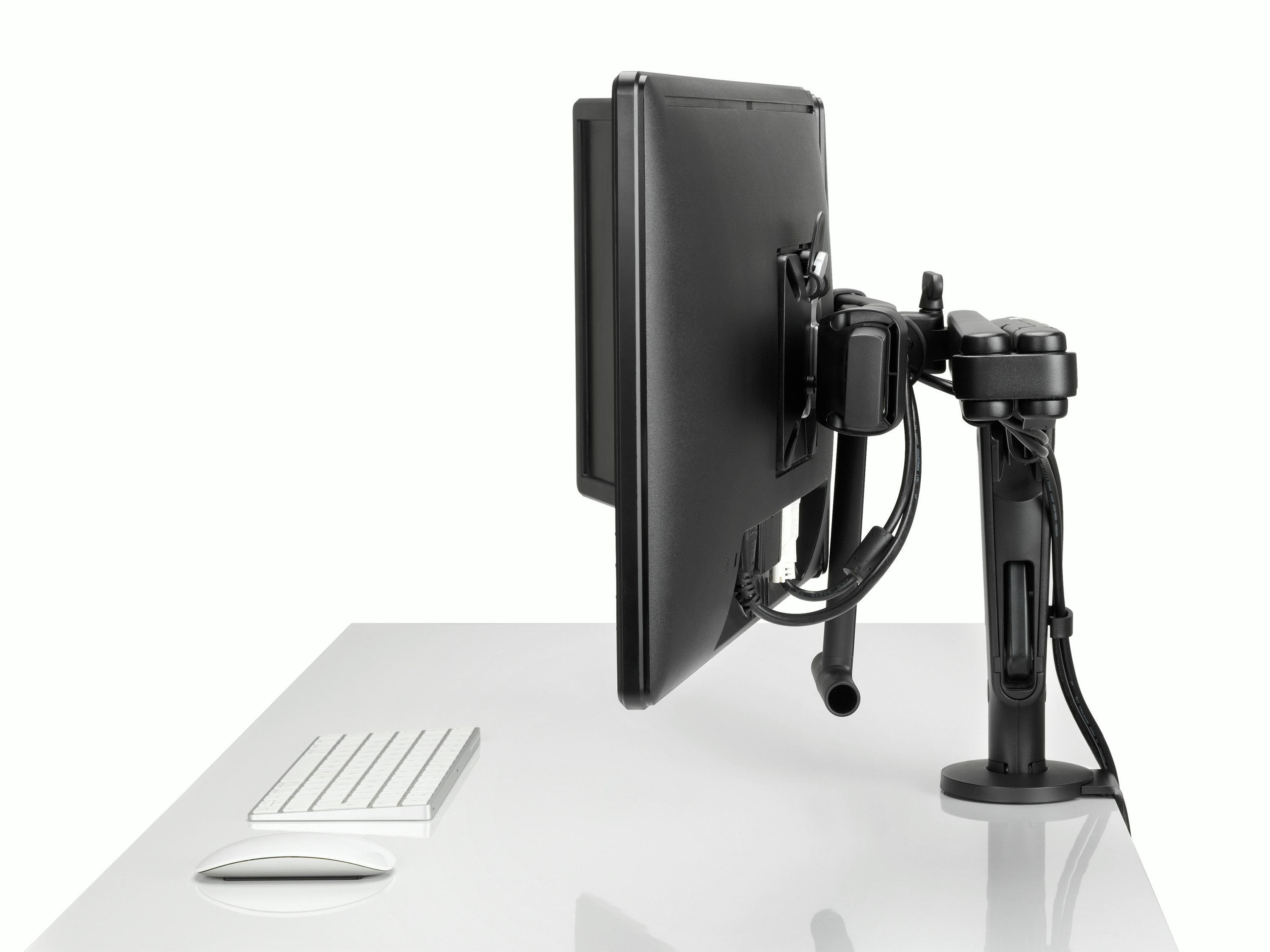 Profile view of two monitors attached to a black Ollin Monitor Arm in dual configuration, and with the optional dual bar handle added to support ease of adjustment of screen position