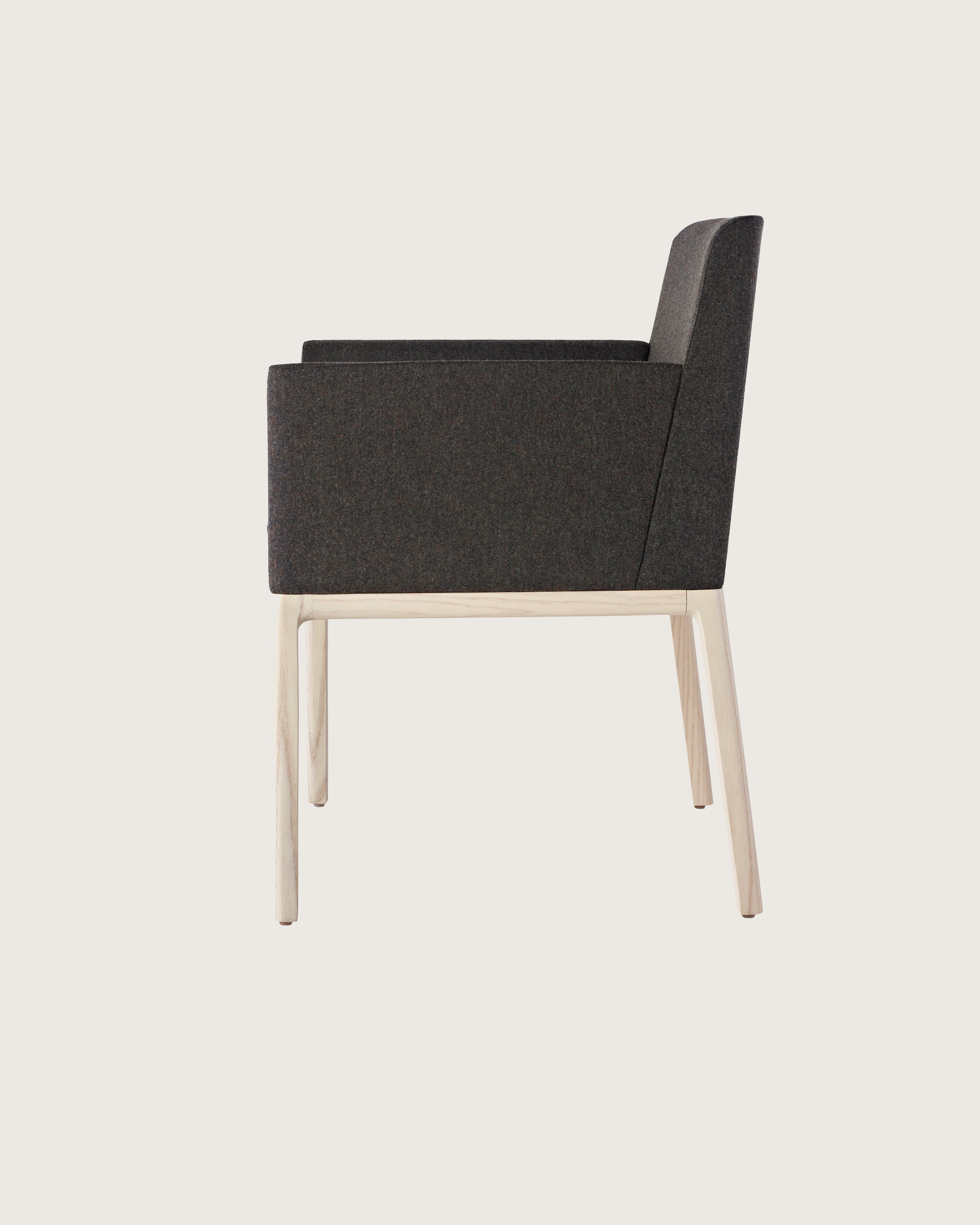 Side view of a Nessel side chair with black fabric upholstery, wraparound arms, and a wood frame with a light finish.