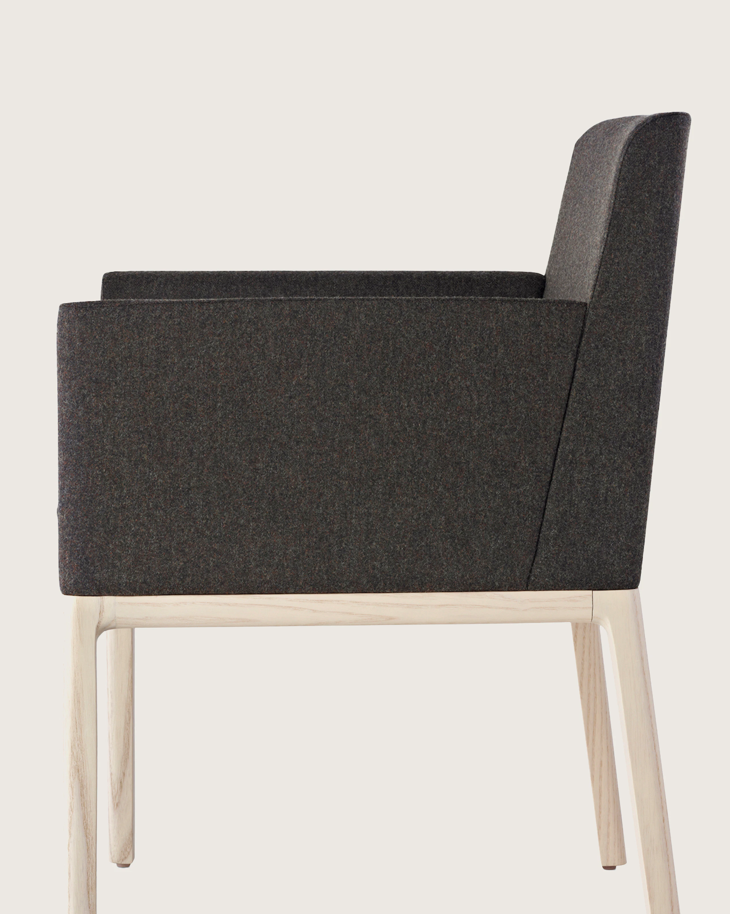 Side view of a Nessel side chair with black fabric upholstery, wraparound arms, and a wood frame with a light finish.
