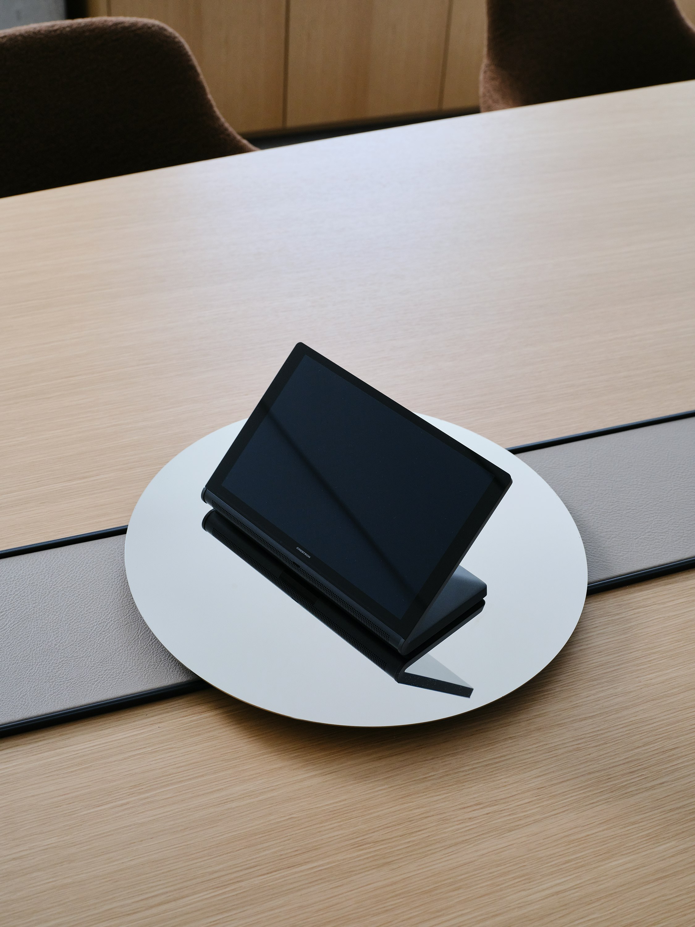 Detail view of the Ascent Conference Table accessory tray in chrome, with the power trough covered in Prone leather in Lute and a Natural Rift Cut Oak tabletop, viewed from above at an angle.