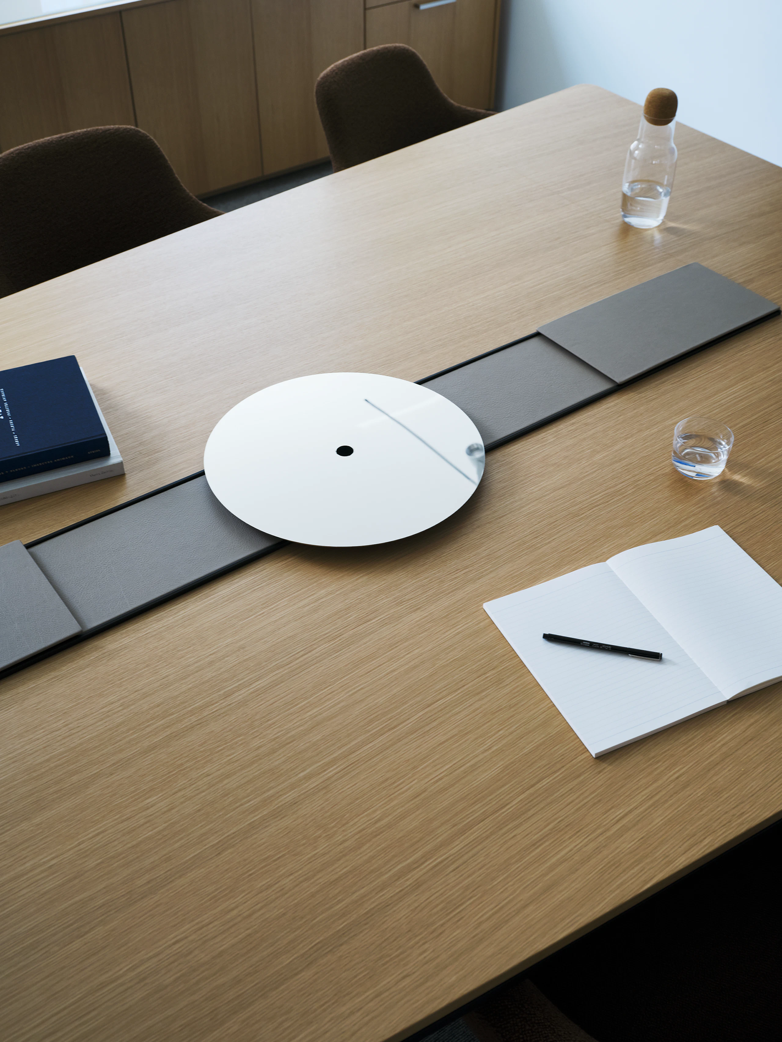 Ascent Conference Table designed by EOOS in Natural Rift Cut Oak with a leather-covered power trough and chrome accessory tray, viewed from above in a conference room setting.