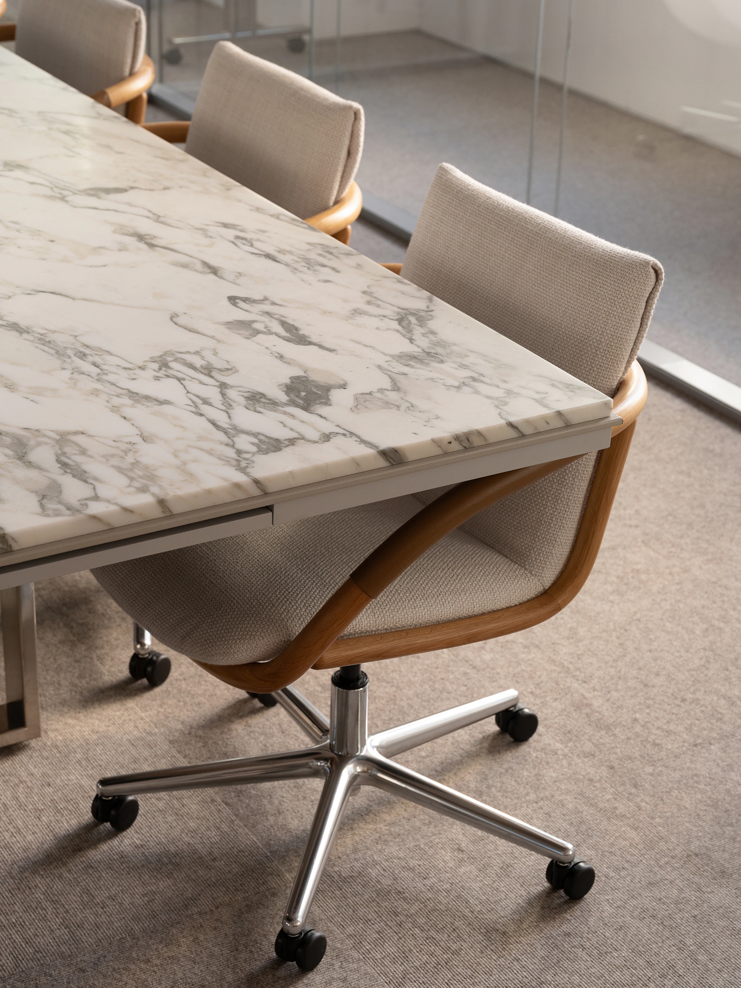 Three Full Loop Chairs designed by EOOS with an Oak frame upholstered with Capri in Snow, with a Highline Conference Table with an Arabescato Corchia marble top, viewed at an angle.