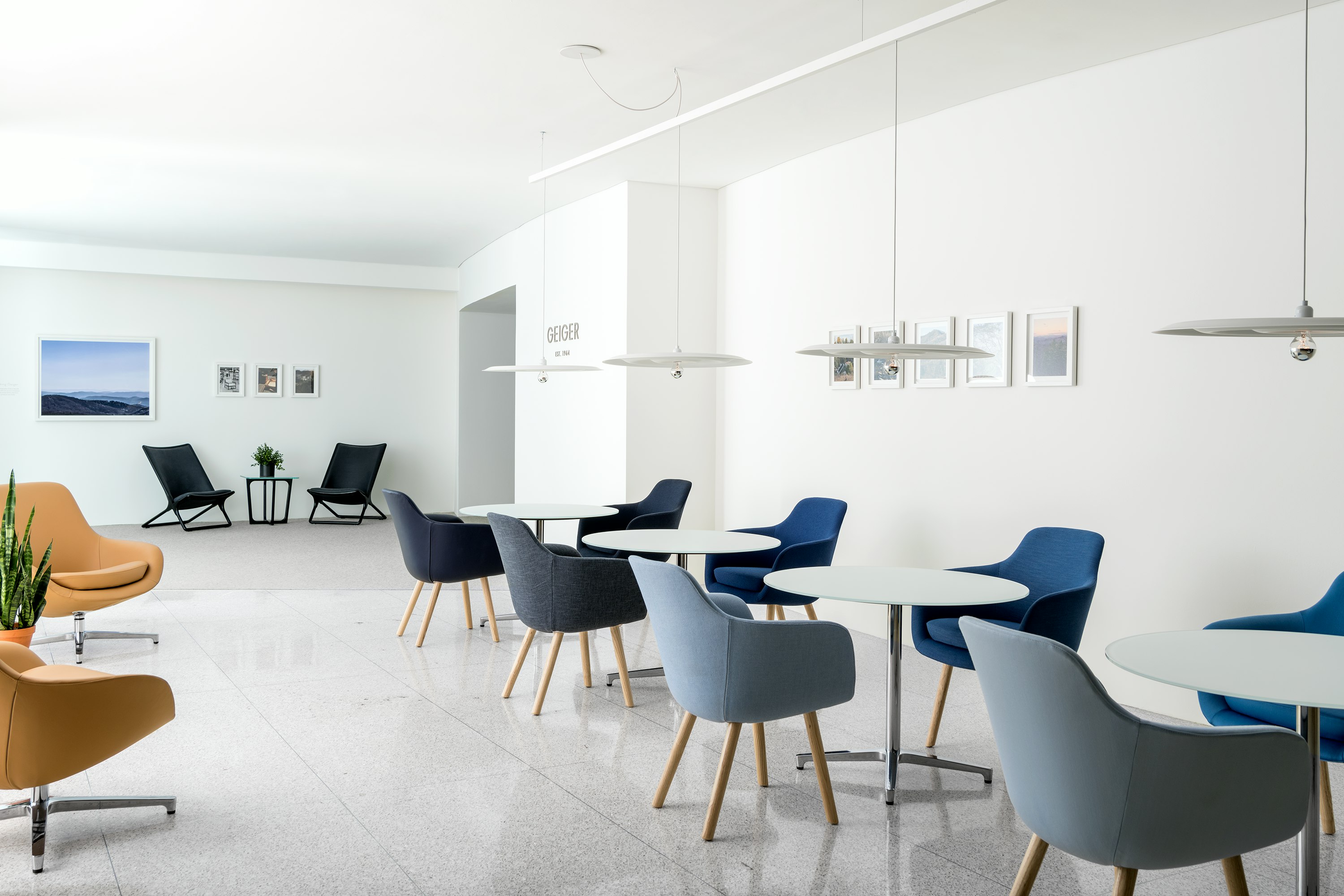 An informal meeting space featuring round Saiba occasional tables with Saiba Side Chairs upholstered in various shades of blue.