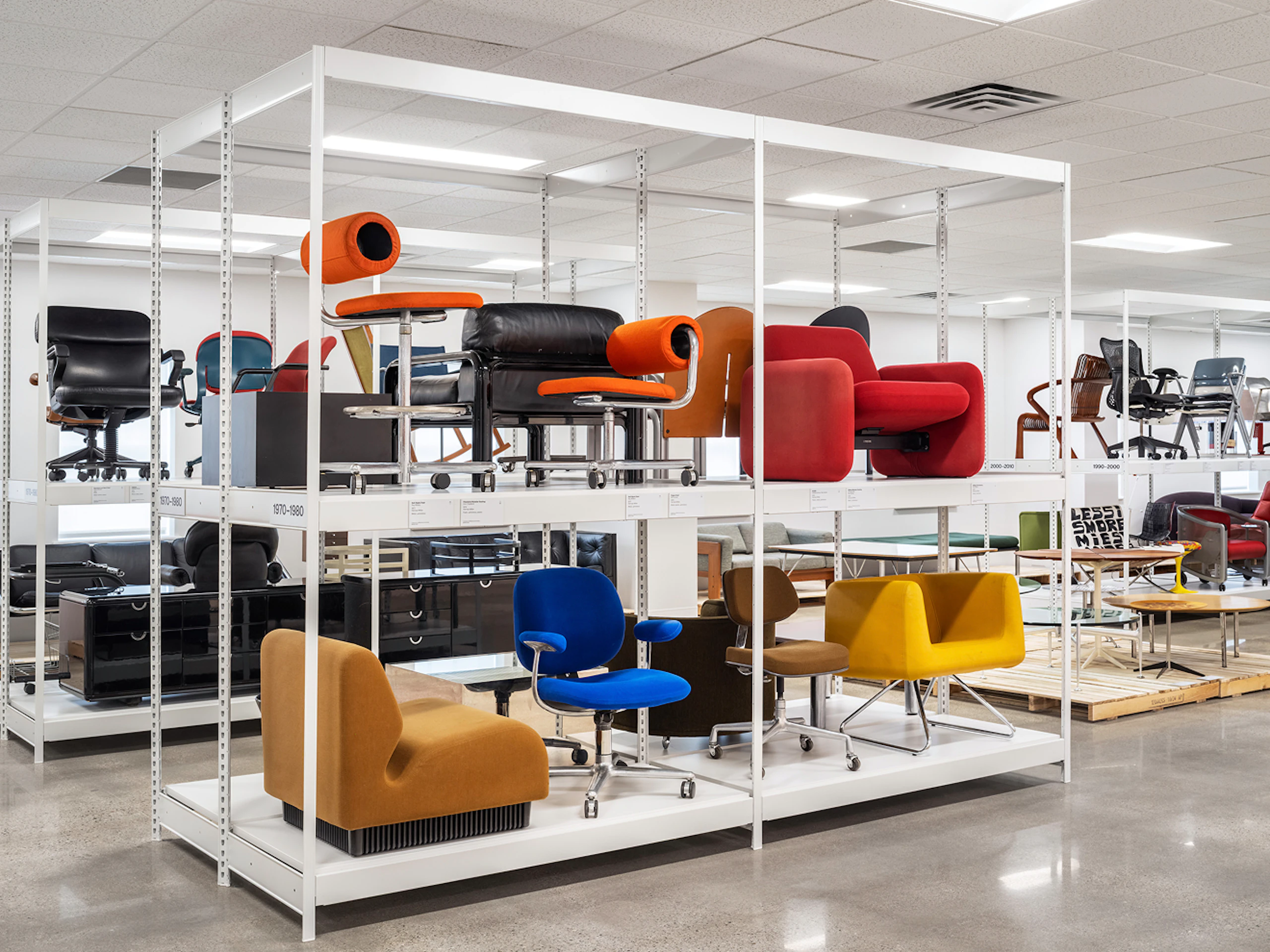 A variety of colourful seating from the MillerKnoll collective of brands on display on white racks at the MillerKnoll Archives