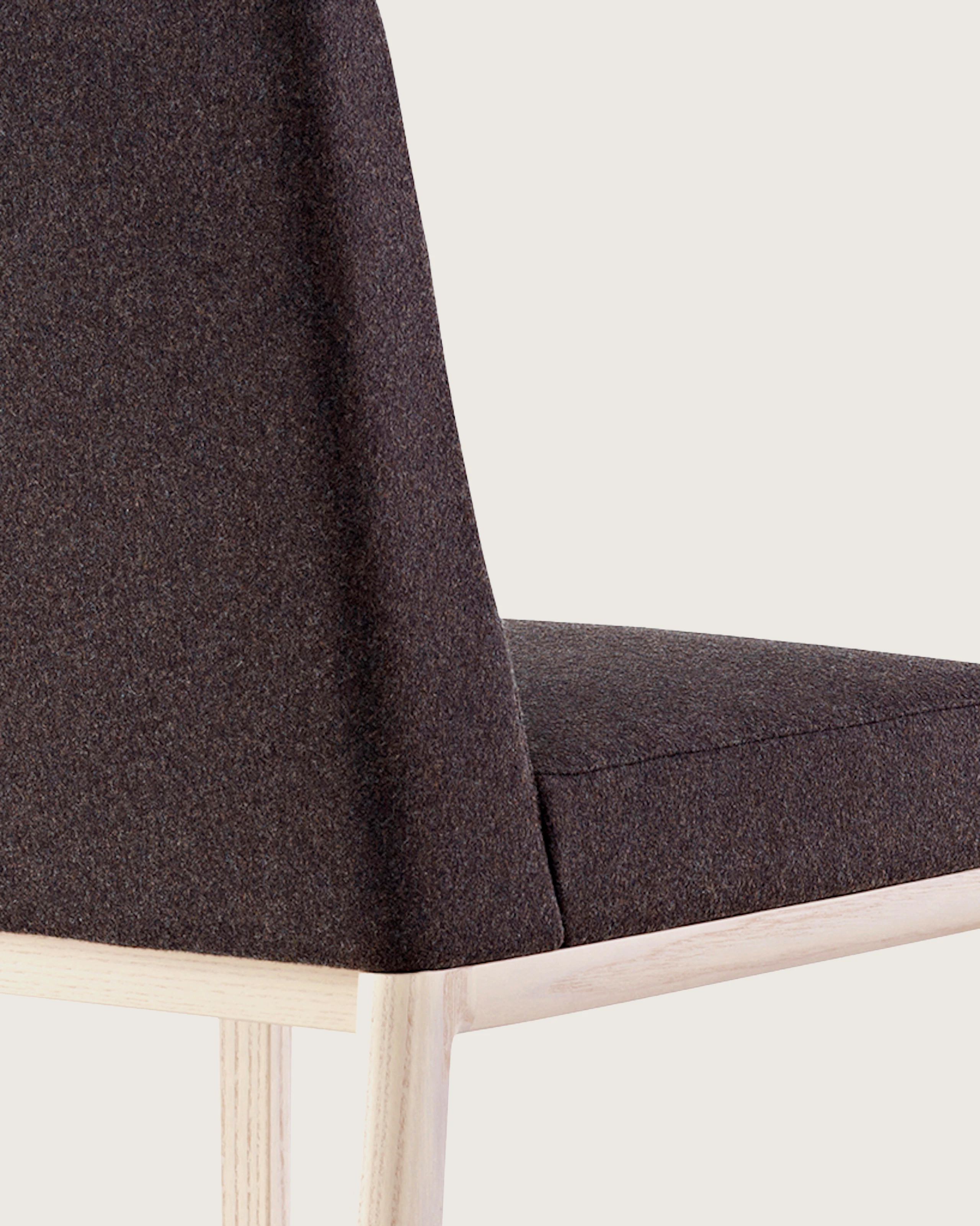 An armless Nessel side chair with black fabric upholstery and a wood frame with a light finish, viewed from behind at an angle.