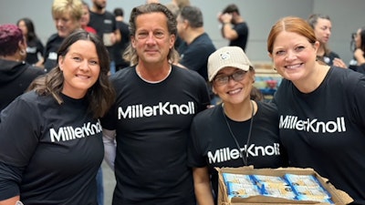 Four smiling MillerKnoll associates wearing black and white MillerKnoll shirts while volunteering at Hand2Hand.