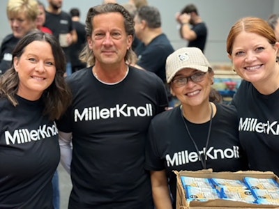 Four smiling MillerKnoll associates wearing black and white MillerKnoll shirts while volunteering at Hand2Hand.