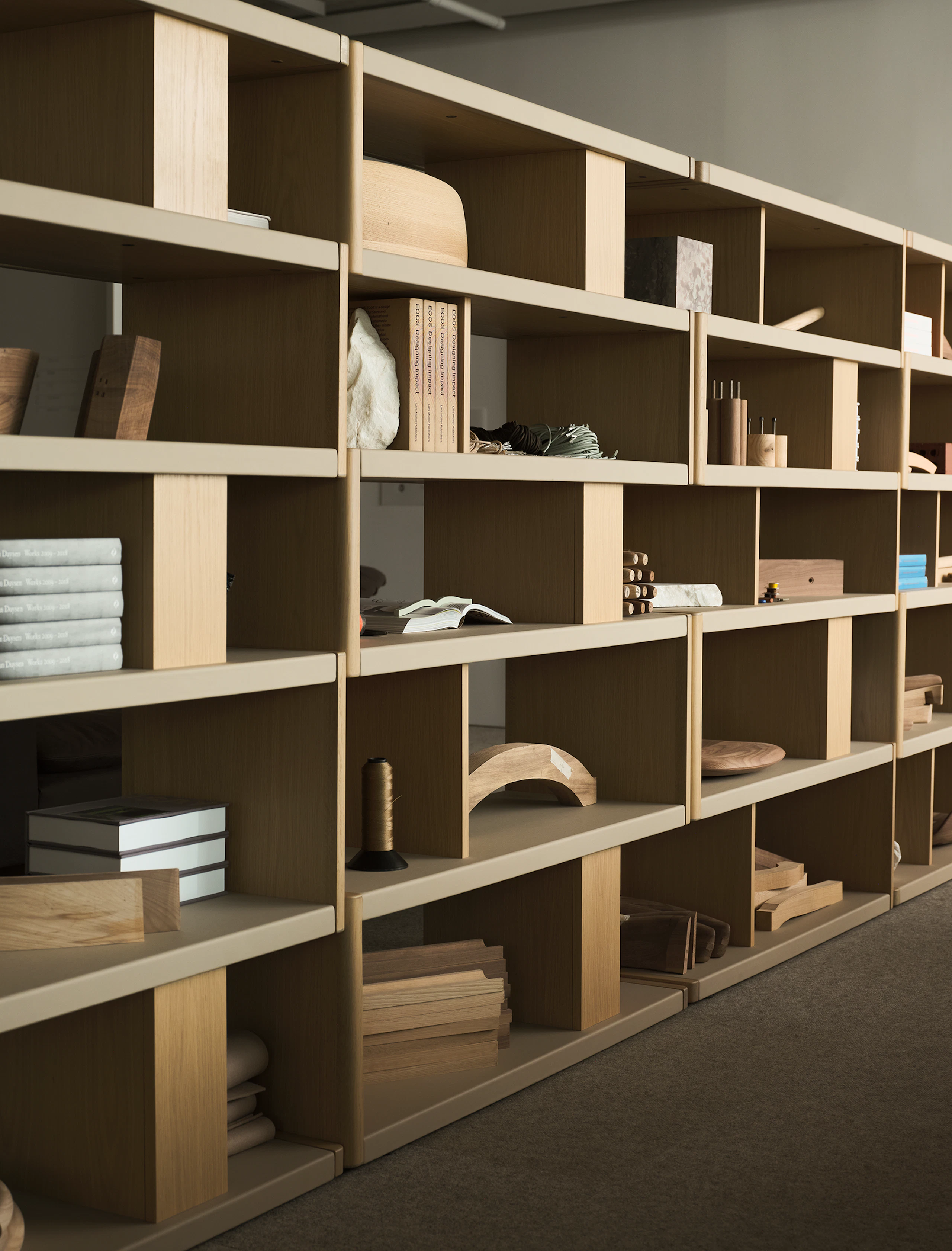 Various New Canaan Tall Bookshelves in Light Oak wrapped with Bristol Leather in Champagne arranged side by side and styled with various objects, viewed at an angle.