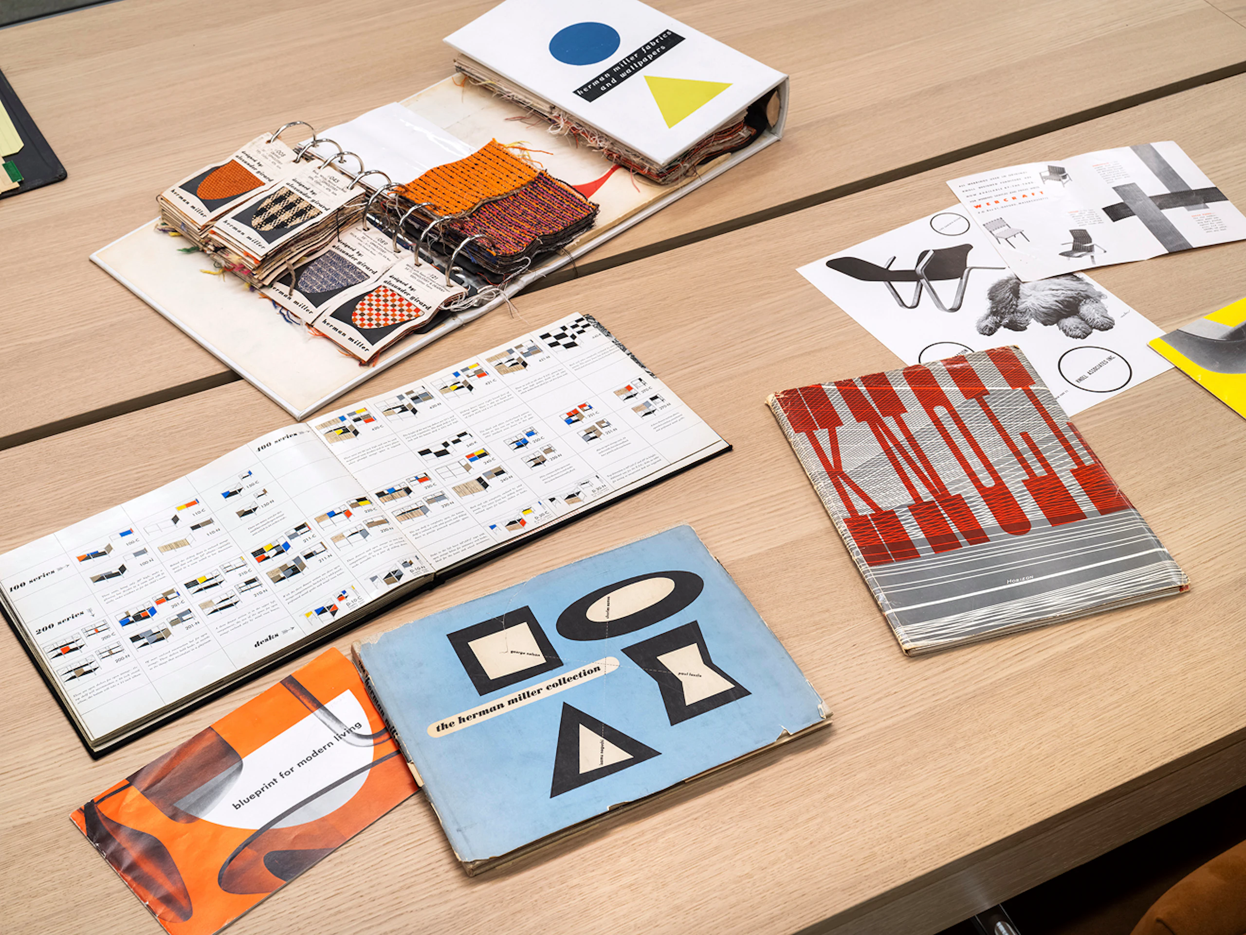 Several pieces of colourful product literature and fabric swatches from Herman Miller, Knoll and others on a wooden table at the MillerKnoll Archives reading room