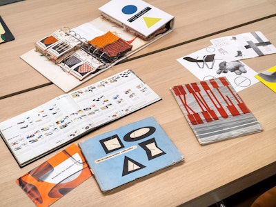 Several pieces of colorful product literature and fabric swatches from Herman Miller, Knoll, and others on a wooden table at the MillerKnoll Archives reading room