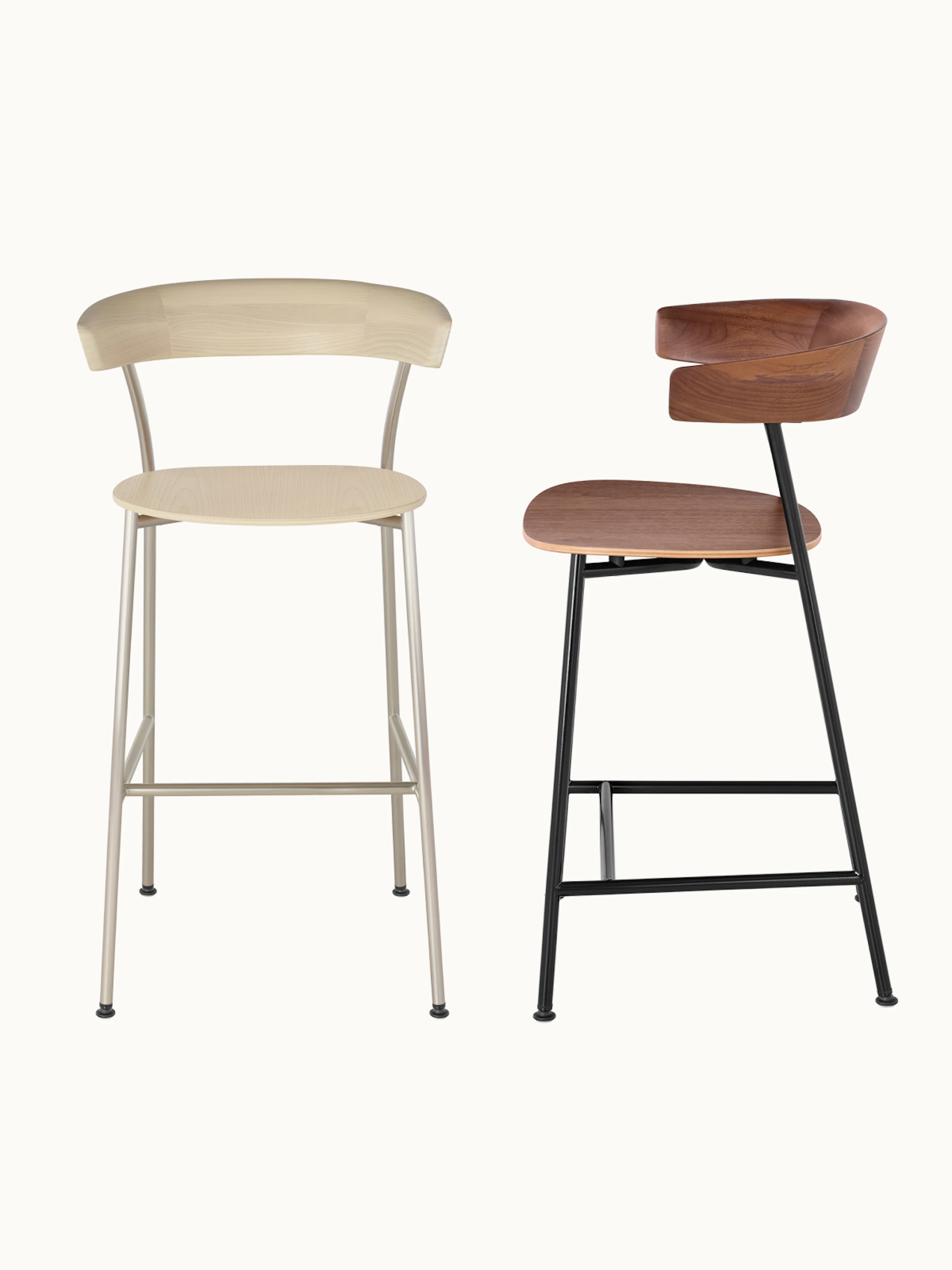 Two bar-height Leeway Stools designed by Keiji Takeuchi, one Oak with a light metal frame front-facing, one in Walnut with a black metal frame shown at an angle, on a white sweep.