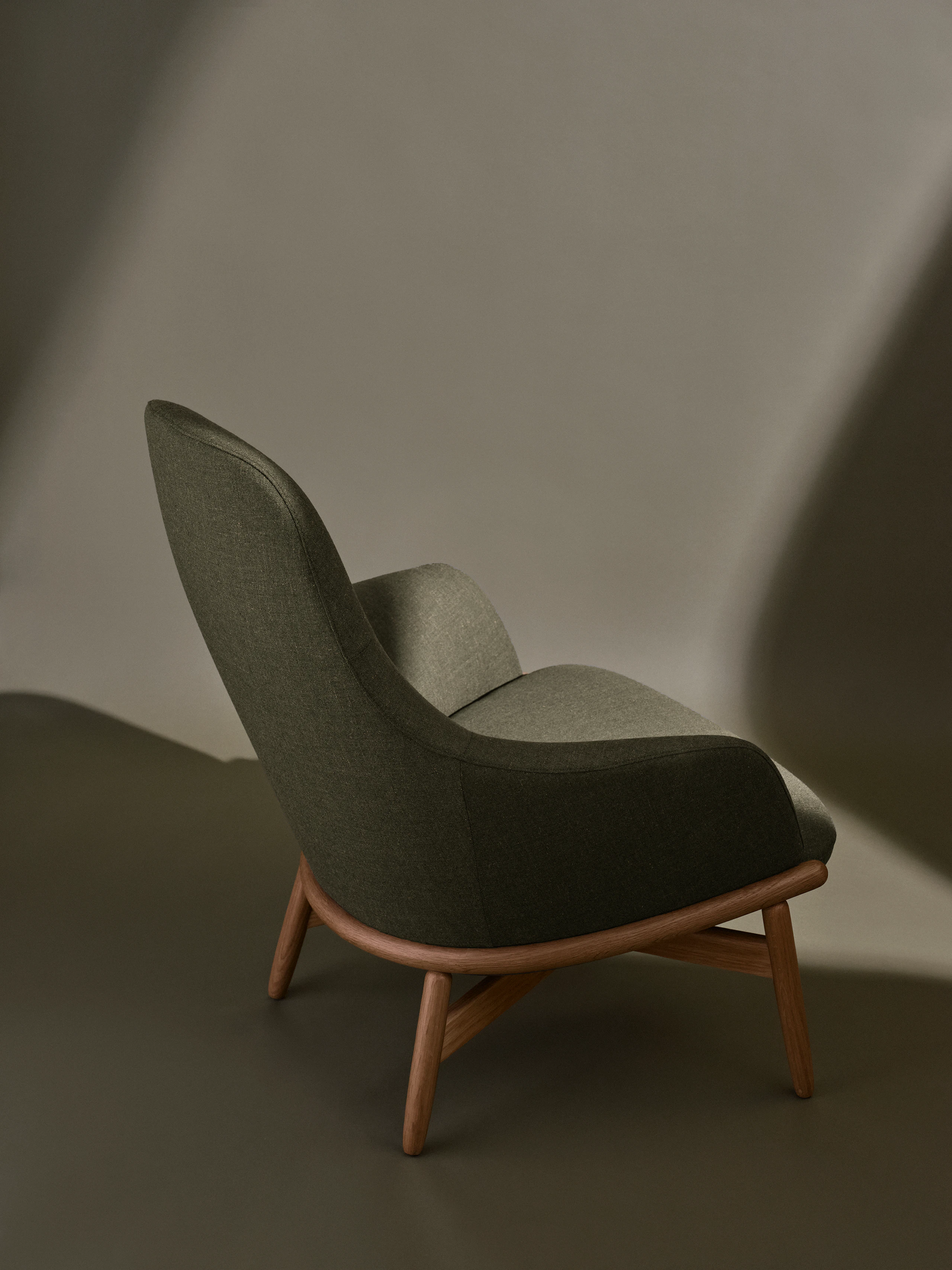 High-Back Reframe Lounge Chair designed by EOOS with an Oak frame upholstered with Rowan in Zucchini, viewed from behind at an angle against a neutral studio background.