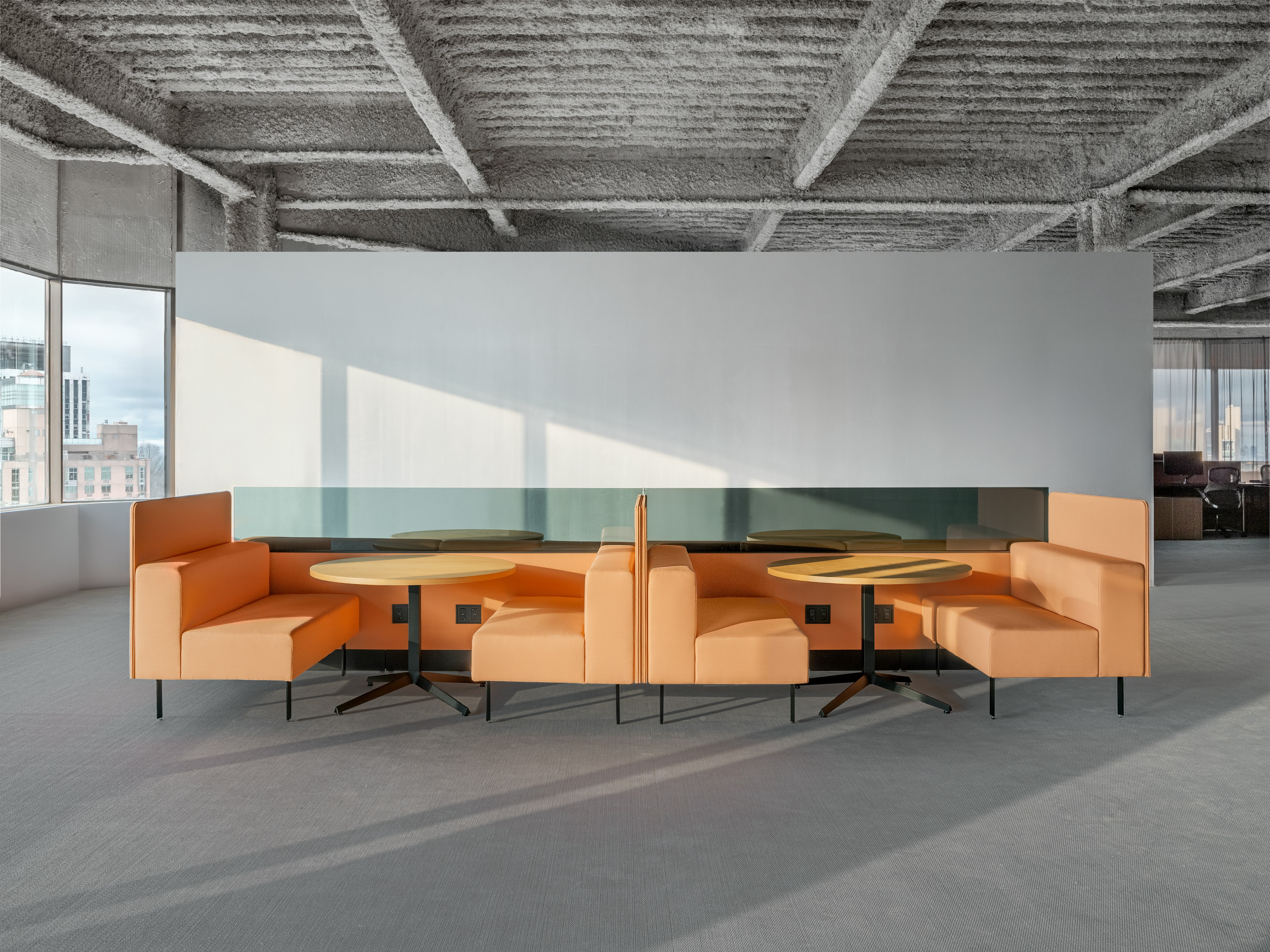 A group of working lounge seats are configured to create two small work settings. Each setting has two booths with a small meeting table between the seats and the work spaces are divided by privacy screens.
