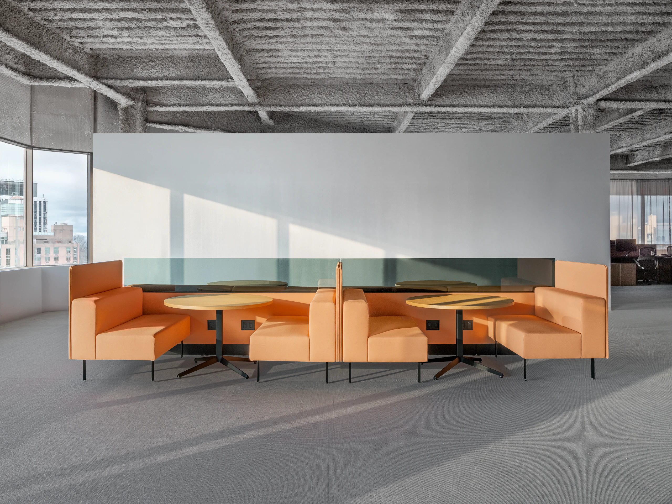 A group of working lounge seats are configured to create two small work settings. Each setting has two booths with a small meeting table between the seats and the work spaces are divided by privacy screens.