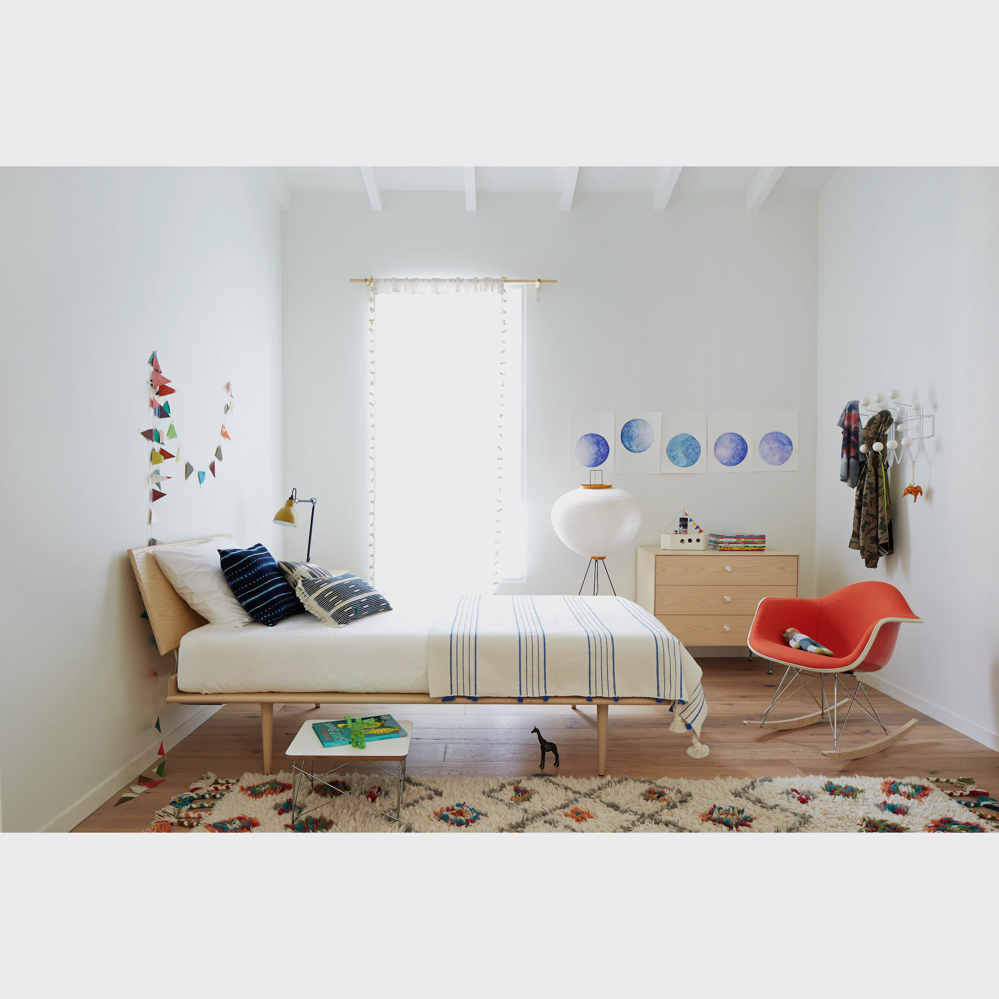 Lifestyle shot of a child's bedroom with a light wood 3-drawer chest and red chair.
